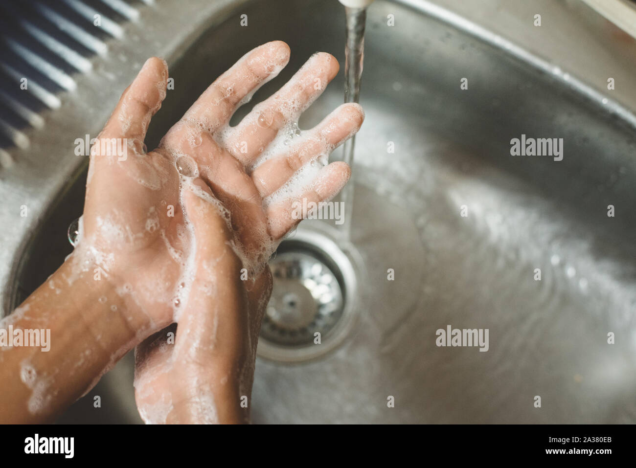 Primo piano di un ragazzo di lavaggio a mano insaponata contro il lavandino. Concetto di igiene delle mani e global handwashing day Foto Stock