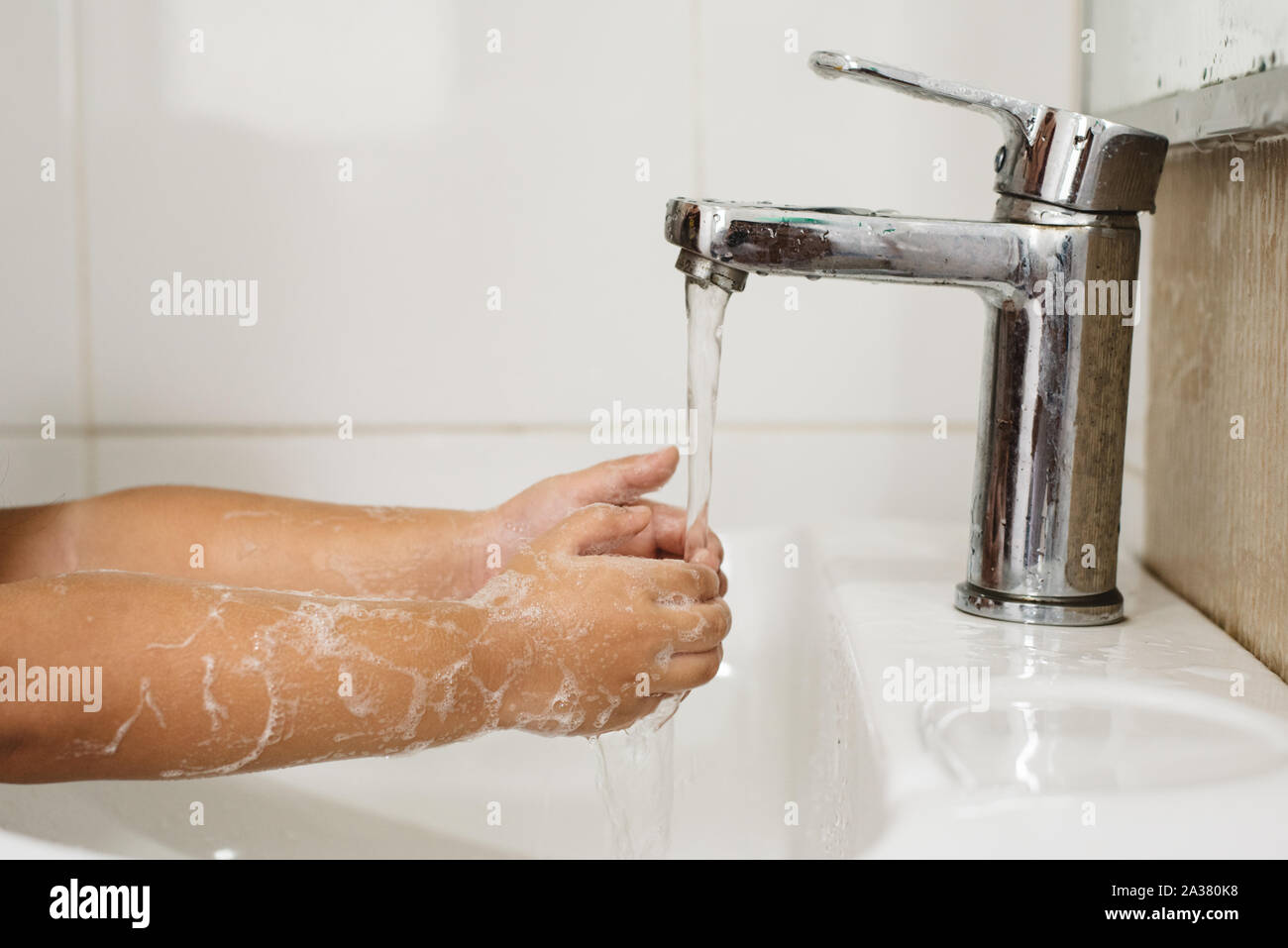 Lavaggio del bambino la sua mano nel lavandino. concetto di igiene delle mani, health care e global handwashing day. Messa a fuoco selettiva sul rubinetto Foto Stock
