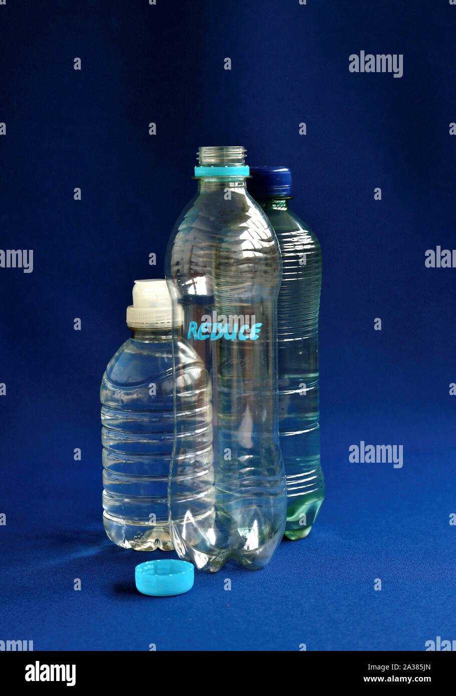 Piccola bottiglia di plastica con la parola ridurre (inquinamento ambientale concetto) Foto Stock