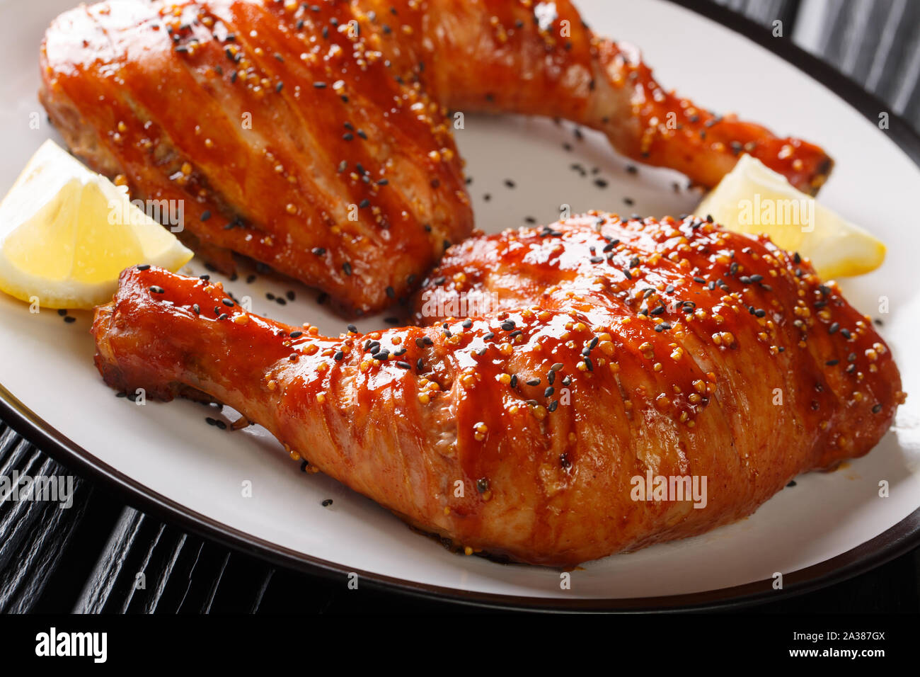 Tradizionale appiccicosa vetrate di cosce di pollo servito con il limone closeup su una piastra sul tavolo orizzontale. Foto Stock