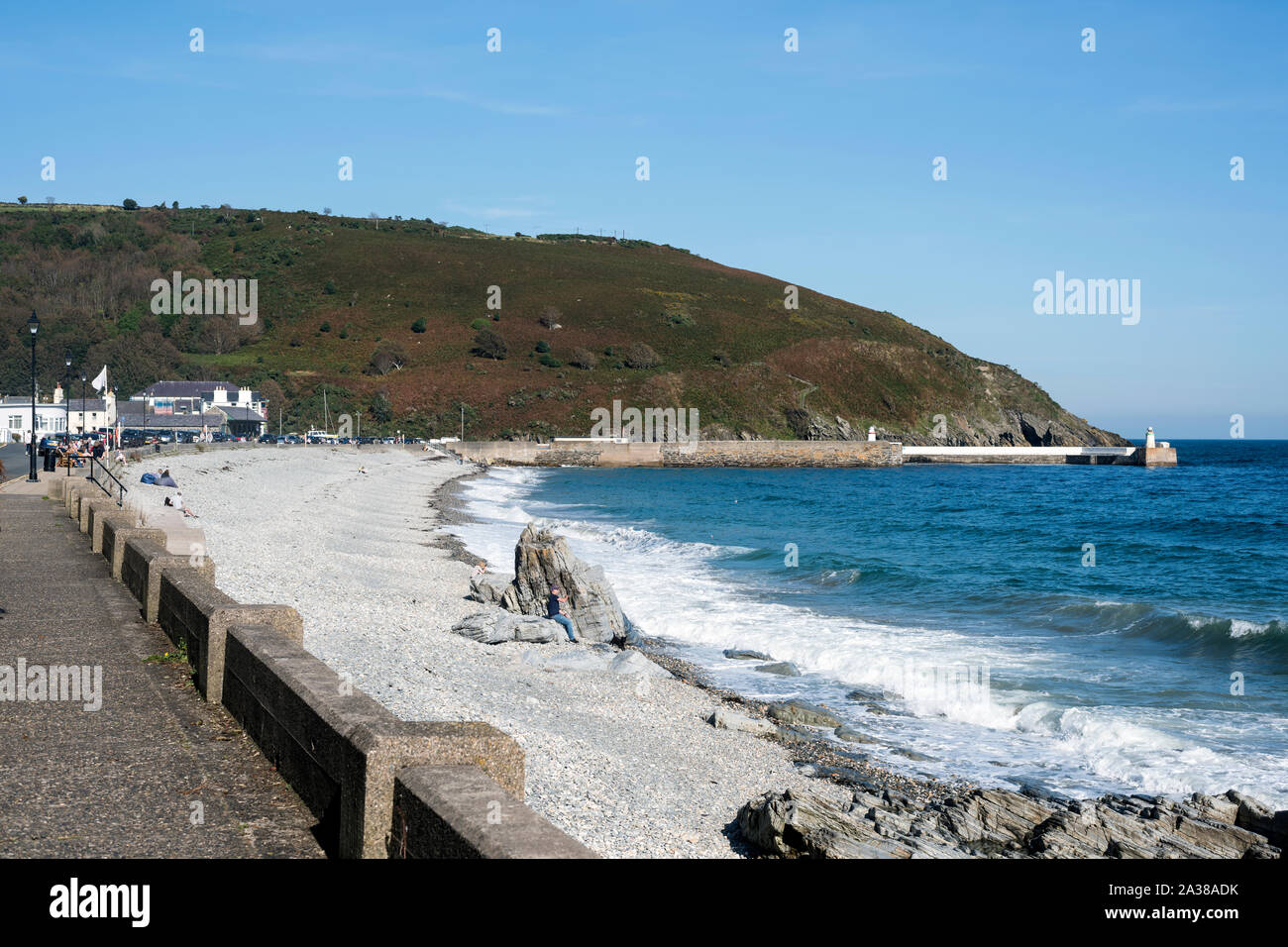 Vista da Nord lungo la spiaggia sassosa e il litorale a Laxey, Isola di Man con spiaggia, grande roccia, seascape e parte promenade in una giornata di sole. Foto Stock