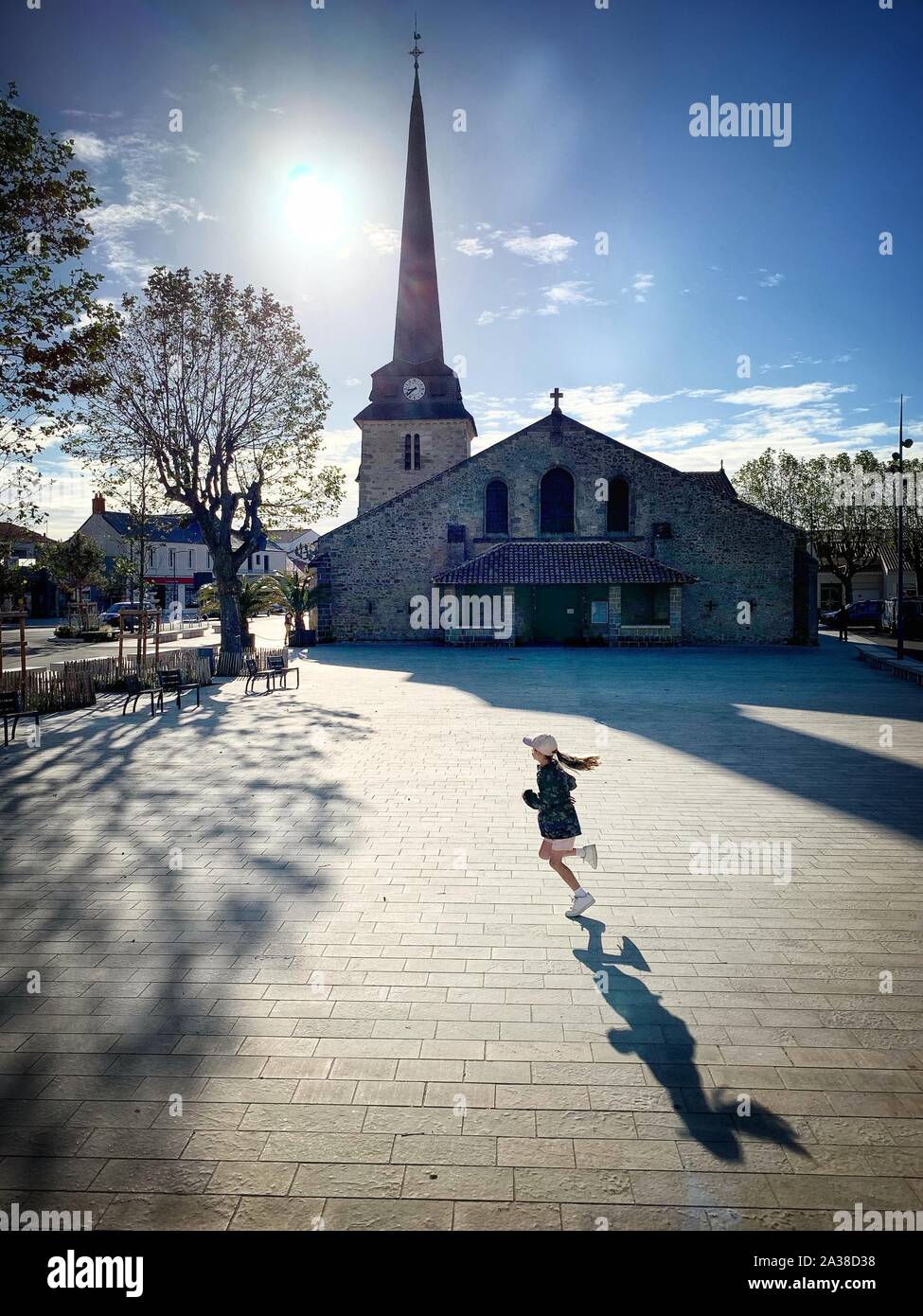 Bambina in esecuzione passato una chiesa di Saint Jean de Monts, Vendee, Francia Foto Stock