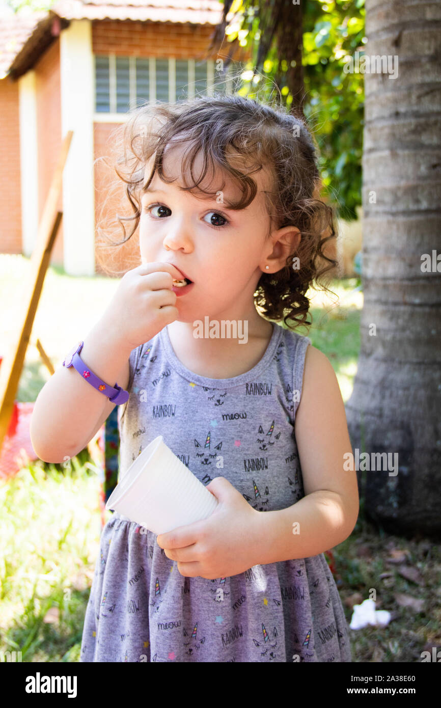 Ragazza in piedi nel parco mangiare popcorn Foto Stock