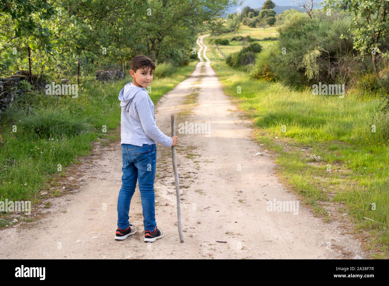 Ragazzo in piedi su un sentiero tenendo un bastone, Spagna Foto Stock