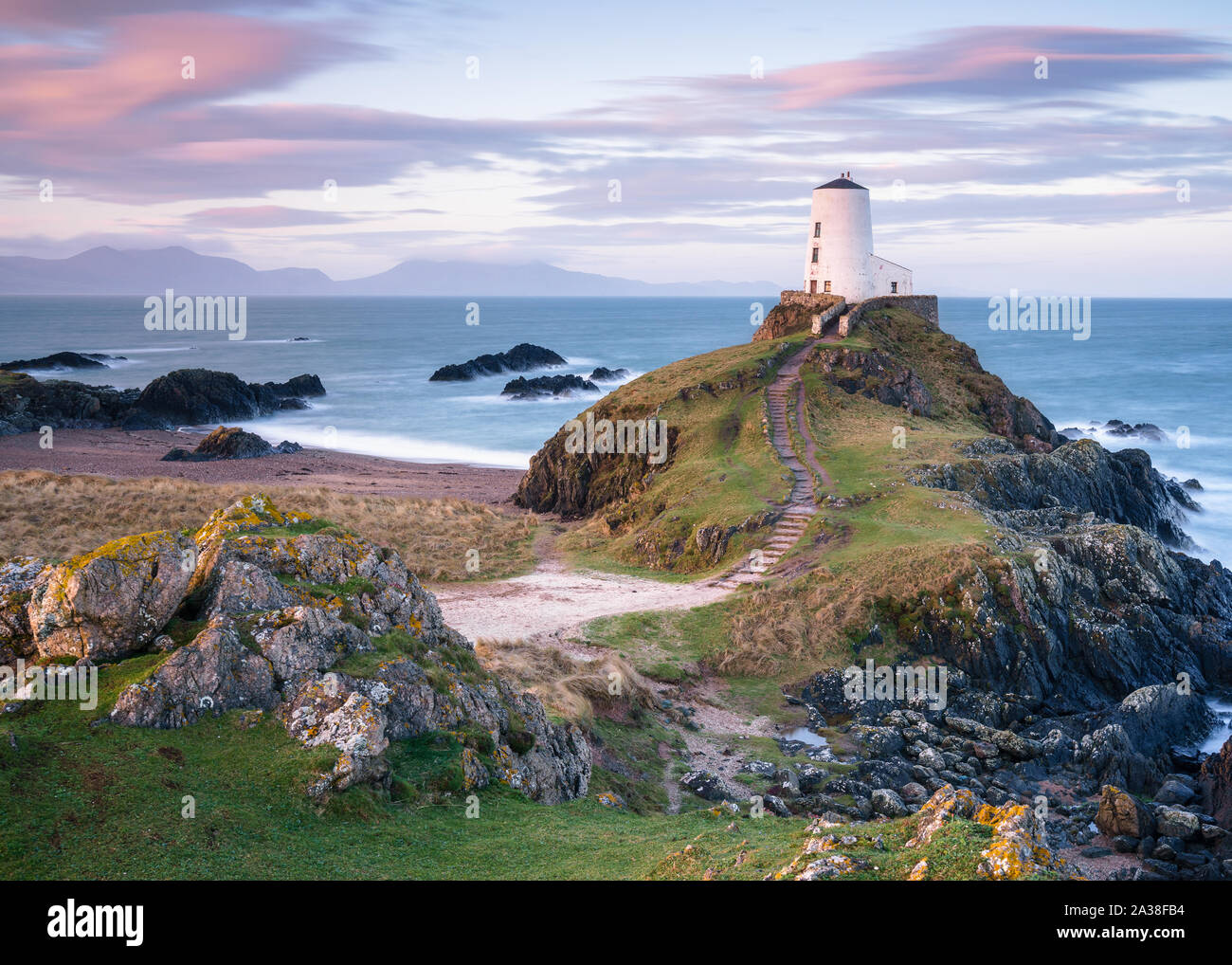 Twr Mawr Faro è illuminata delicatamente come la mattina presto i filtri di luce attraverso il ventoso paesaggio di Llanddwyn Island su Anglesey, Galles del Nord. Foto Stock