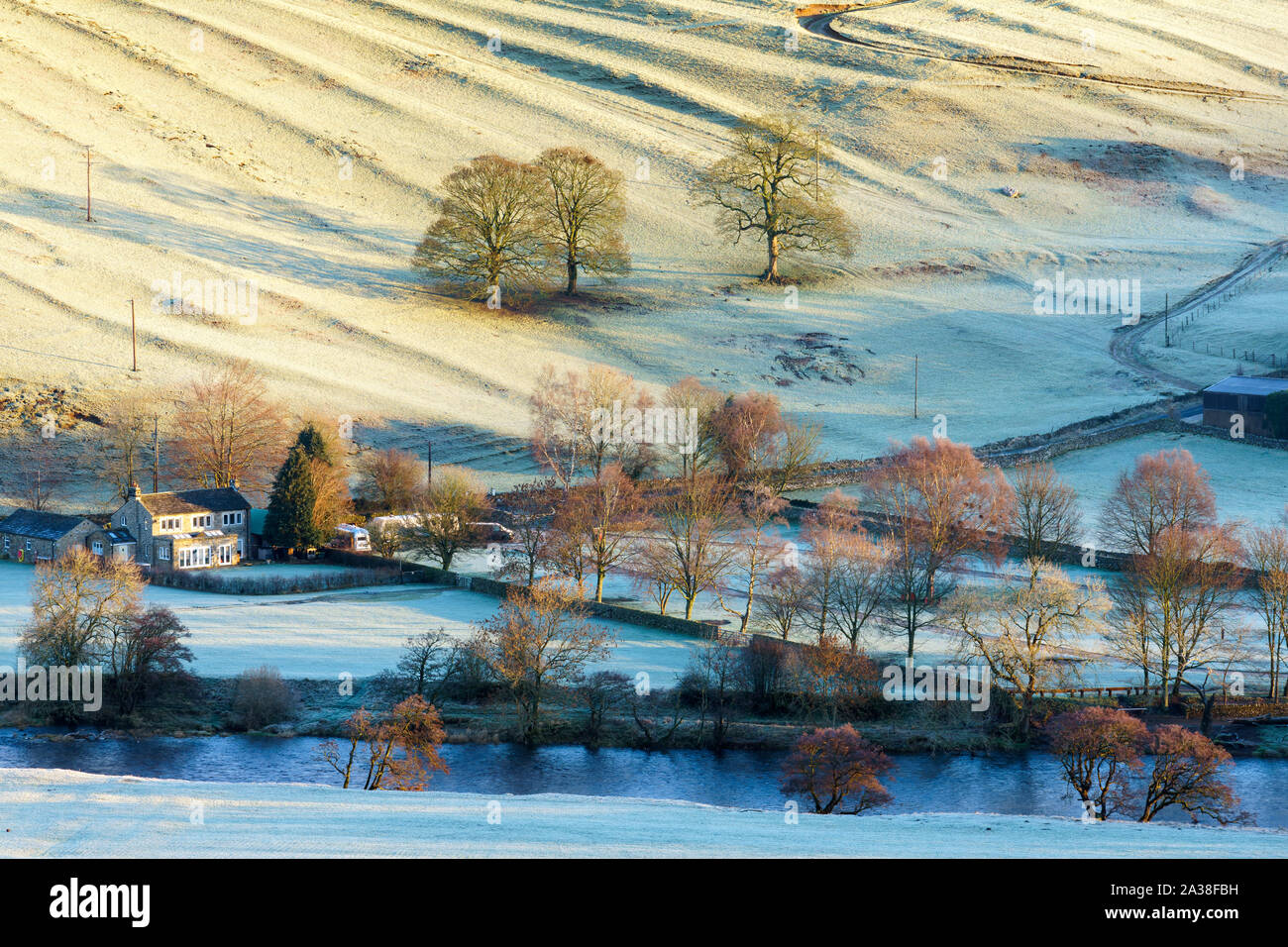 Un agriturismo immerso dal fiume Wharfe nel Yorkshire Dales è illuminata dalla prima luce diretta del sole che sorge su un bellissimo gelido inverno mattina. Foto Stock