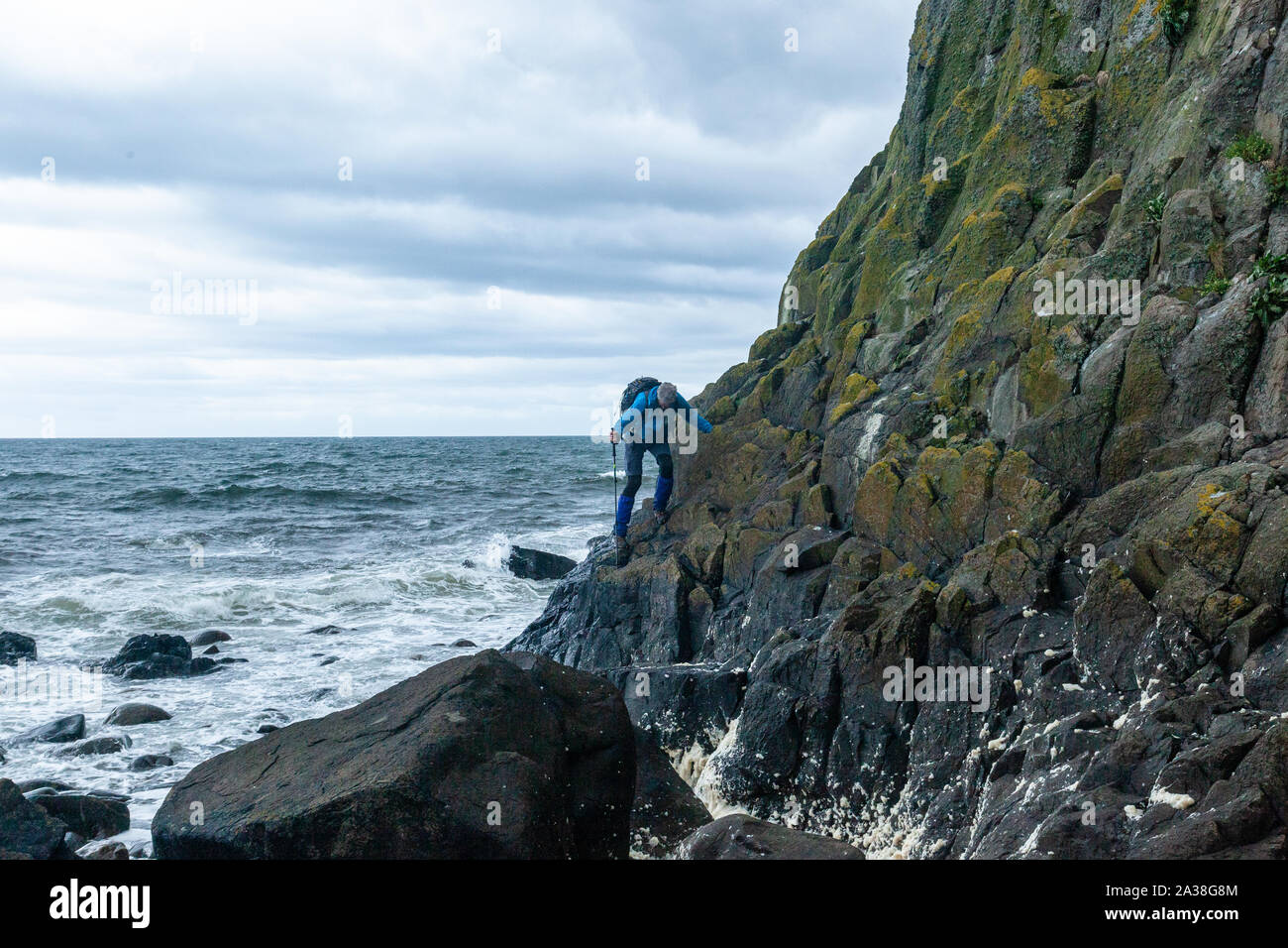 Uomo che passeggia tra le rocce costiere, Bennan Testa, Arran via costiera, Isle of Arran, Scotland, Regno Unito Foto Stock