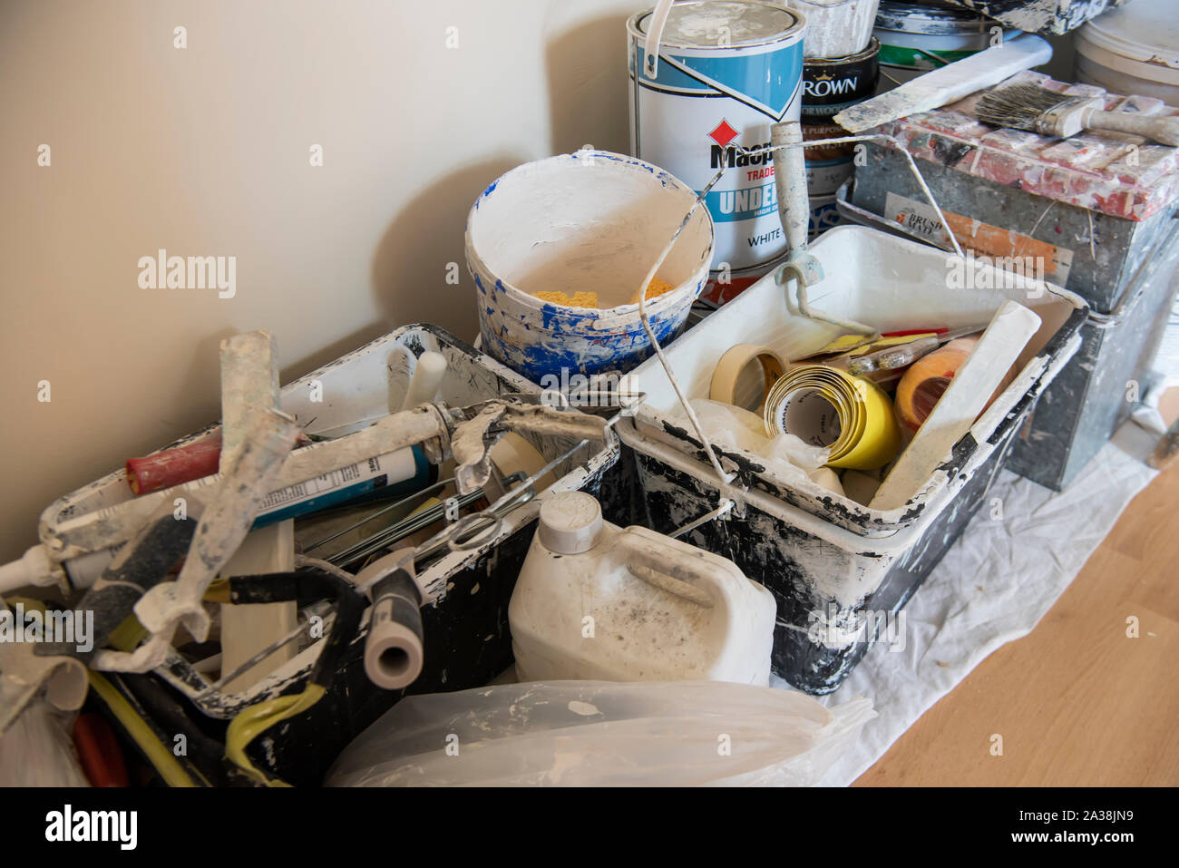 Barattoli di vernice, spazzole, rulli e altre apparecchiature in una sala decorata. Foto Stock