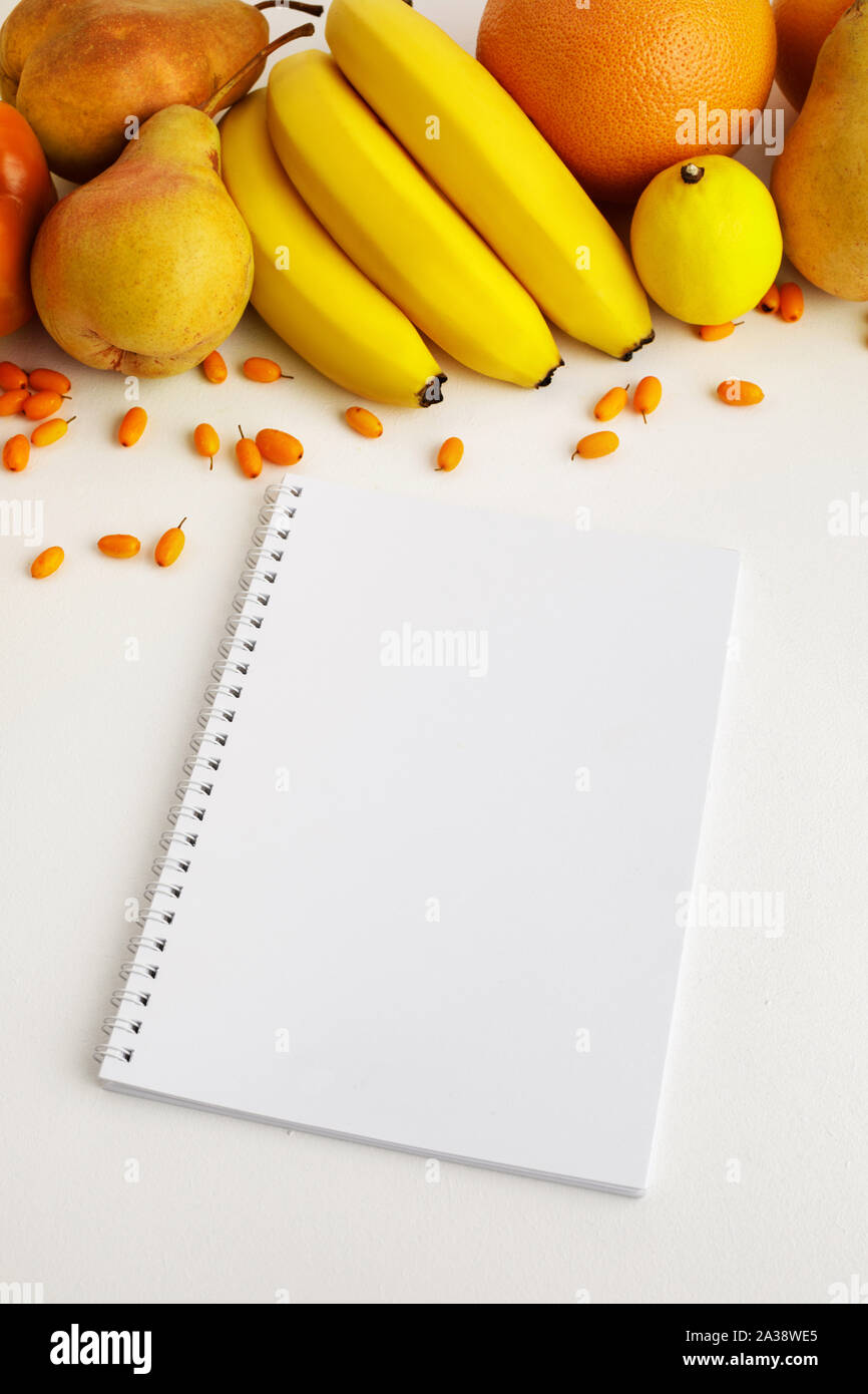Autunno fresco giallo e arancione di frutta e verdura e notebook su sfondo bianco, vista dall'alto. piatto. laici autunno sfondo. Foto Stock