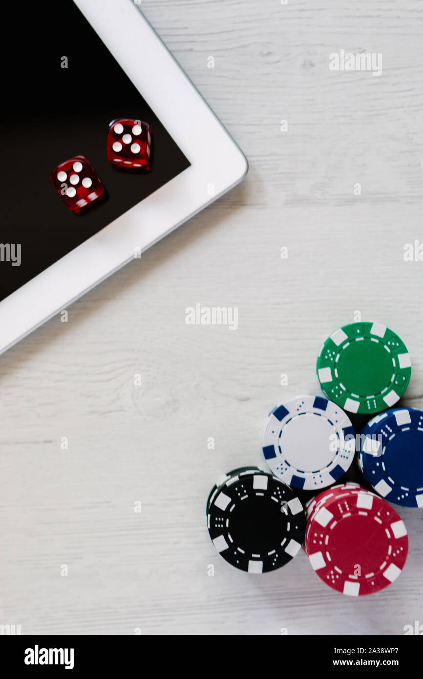 Poker chips e dadi rossi su un tablet con spazio per il testo. Scommesse online e giocare a poker su internet Foto Stock