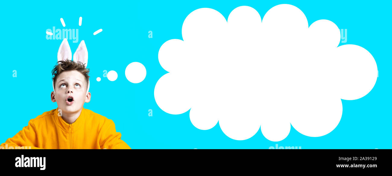 Ragazzo sorpreso in una giacca gialla e le orecchie di lepre su uno sfondo blu Foto Stock