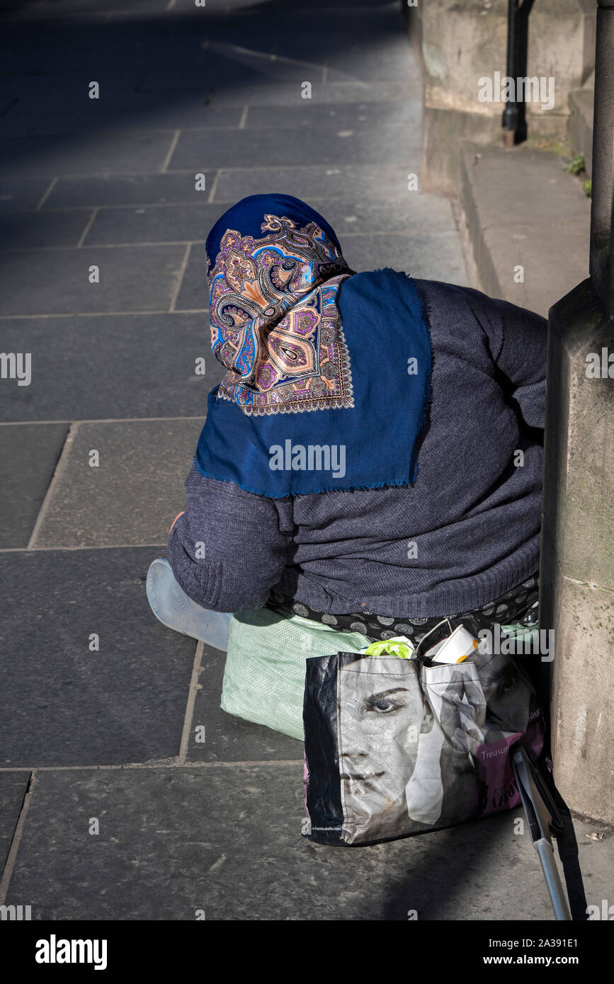 Vista posteriore dell'Est Europen mendicante seduto sul marciapiede su Lothian Road accanto a un Kozmetika Afrodita shopping bag. Foto Stock