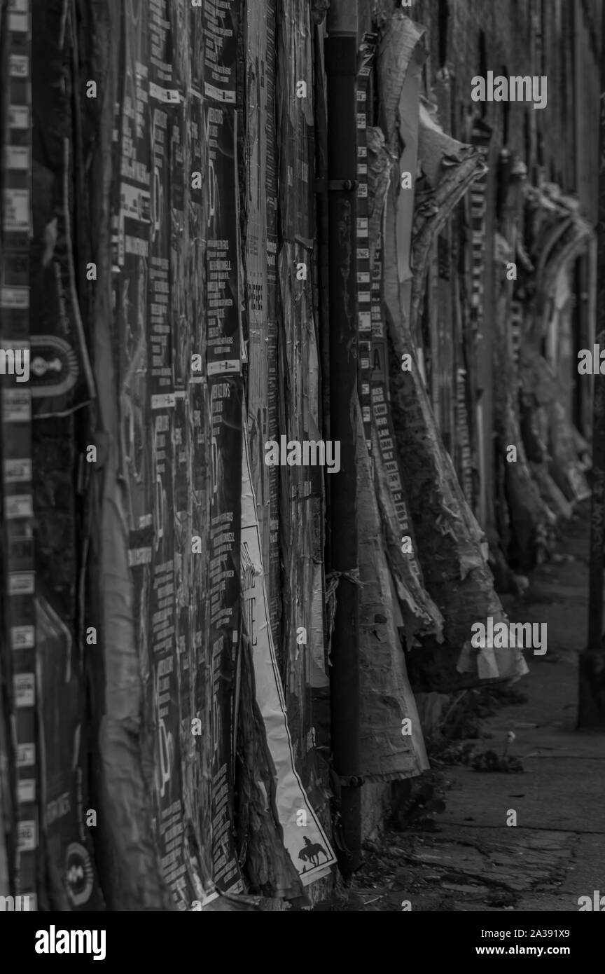 Una foto in bianco e nero di una parete ricoperta con una grande quantità di messaggi pubblicitari. Foto Stock