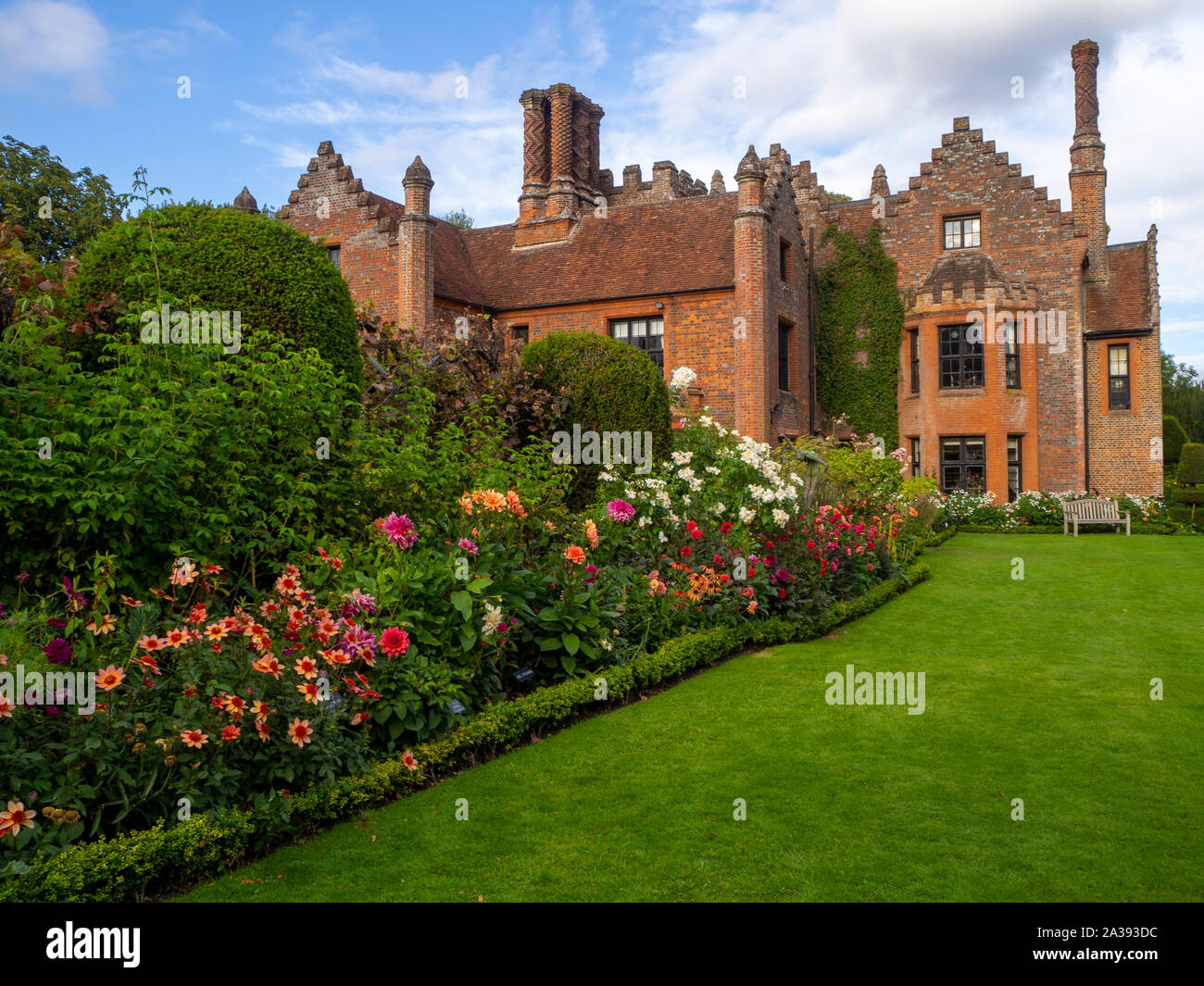 Verso sud confini dello stabilimento, Chenies Manor House e giardino in una bella serata ai primi di settembre.Prato, dalie, arbusti, dotate di architettura di Tudor. Foto Stock
