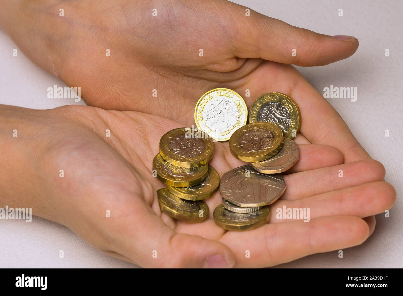 Due mani del bambino con British monete contro uno sfondo bianco Foto Stock