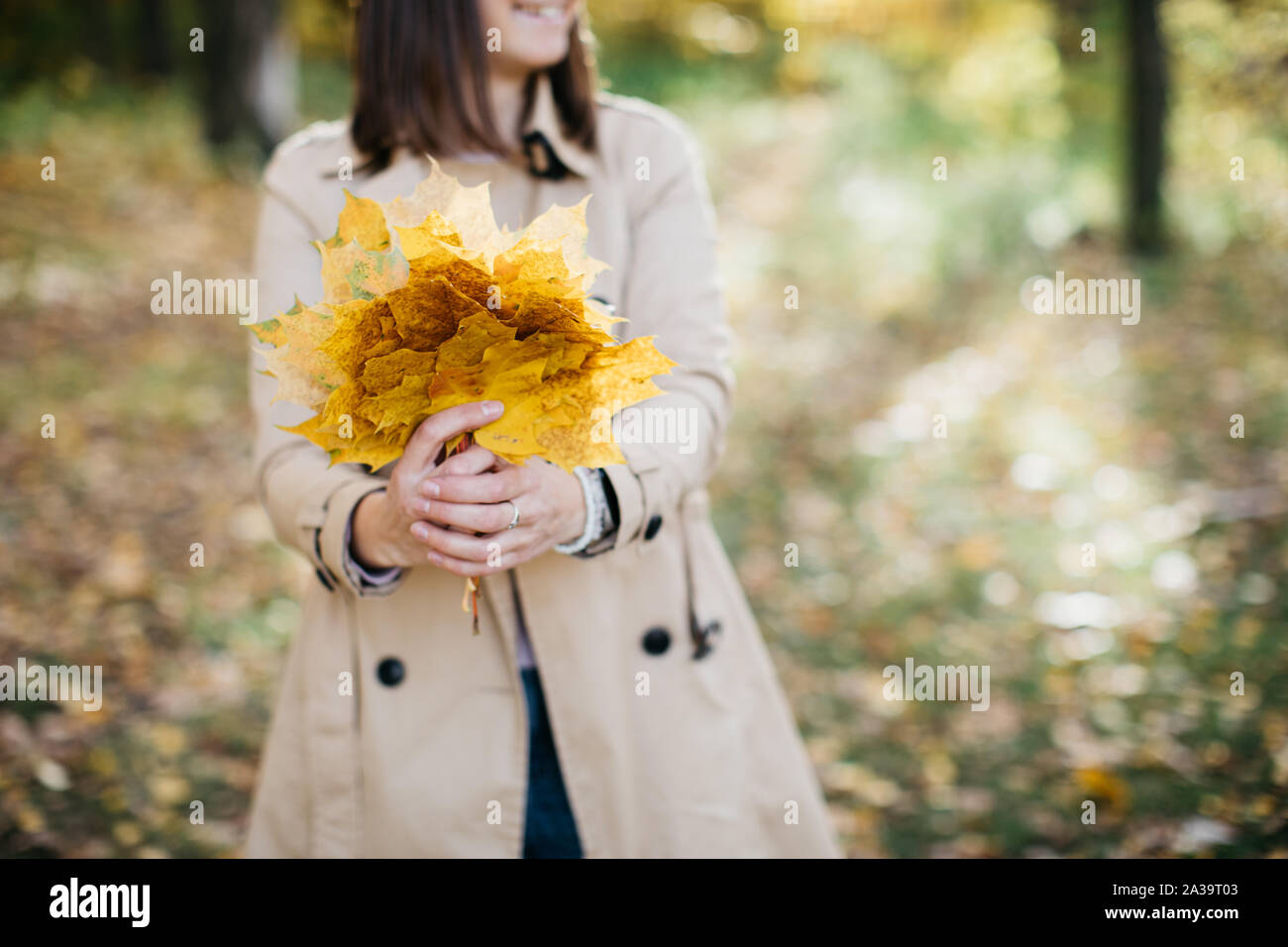 Ragazza nel bosco in autunno con le foglie nelle sue mani. La ragazza è in un ottimo umore e felice Foto Stock