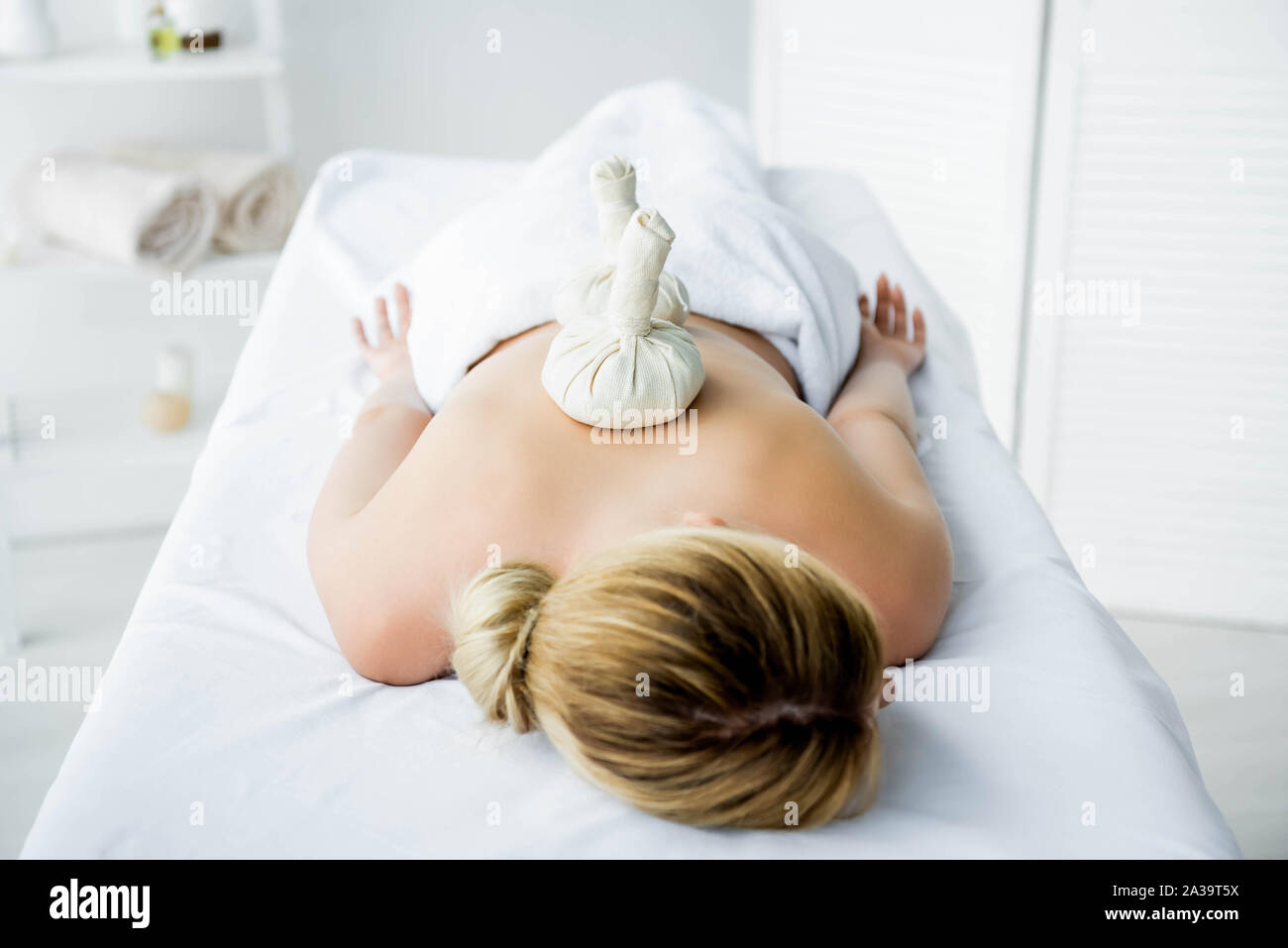 Donna sdraiata sul tappeto di massaggio con sfere di erbe sul retro Foto Stock