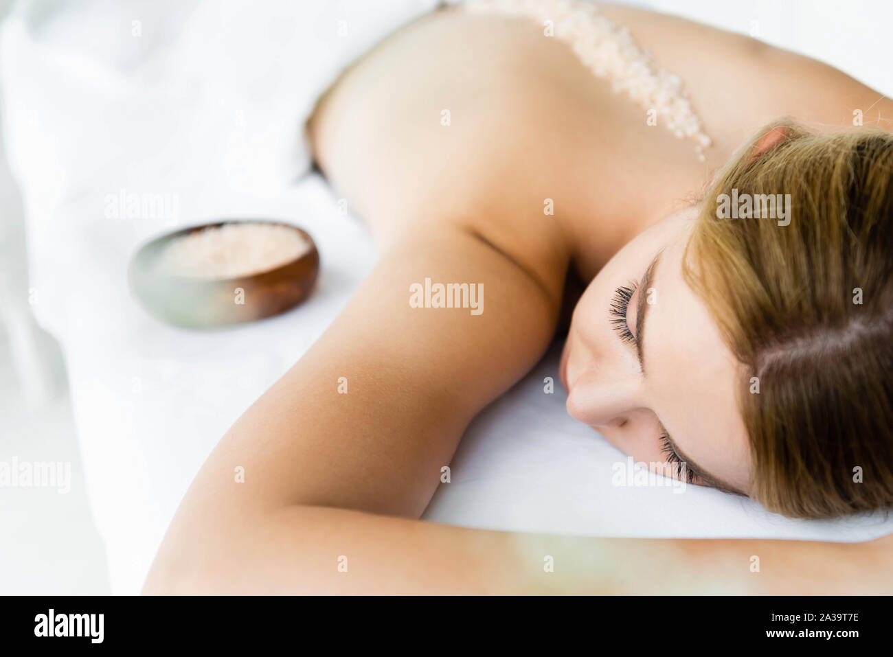 Messa a fuoco selettiva di donna sdraiata sul tappeto di massaggio con sale marino sul retro Foto Stock