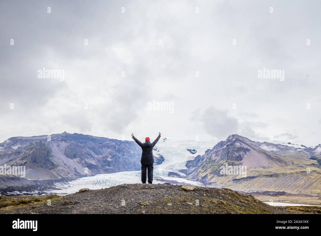 Donna con braccia sollevate guardando al ghiacciaio Vatnajokull, il più grande ghiacciaio d'Europa, si trova sulla costa meridionale dell'Islanda Foto Stock