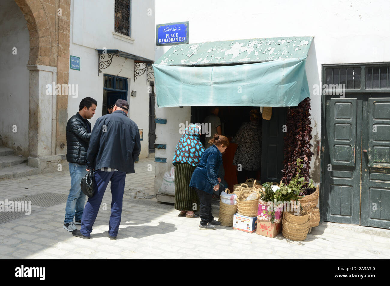 Tunisini in piedi al di fuori di un negozio di alimentari nelle strade pedonali della Hafsia trimestre della medina (città vecchia) di Tunisi, Tunisia. Foto Stock