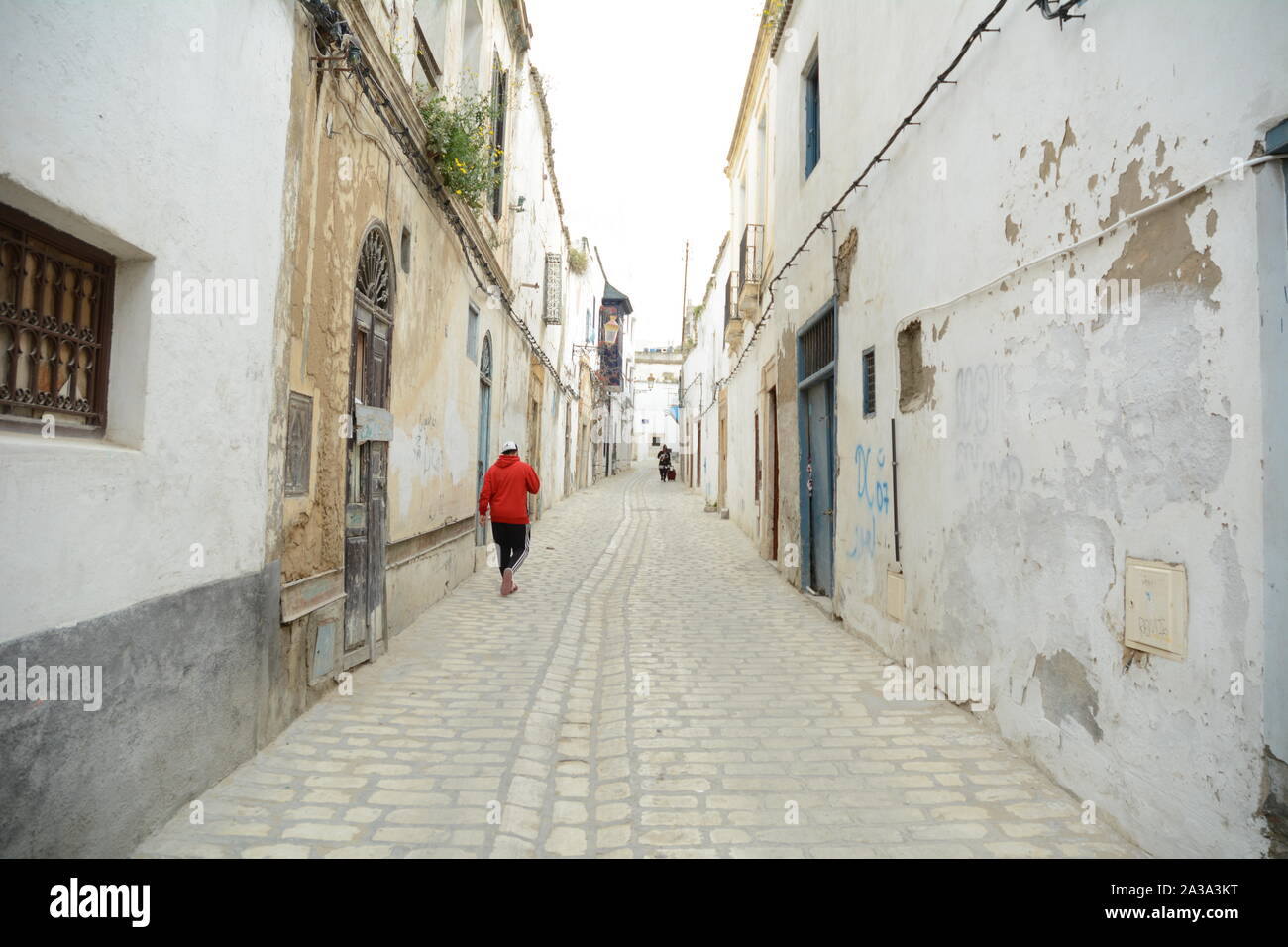 Un giovane uomo tunisino camminando attraverso le strade pedonali del quartiere Hafsia della medina (città vecchia) di Tunisi, Tunisia. Foto Stock