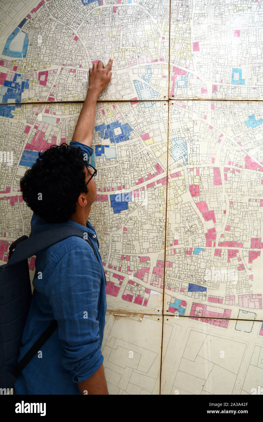 Uno studente tunisino punti su un vecchio muro mappa della medina di Tunisi a un patrimonio architettonico organizzazione nel centro storico della città, Tunisia. Foto Stock
