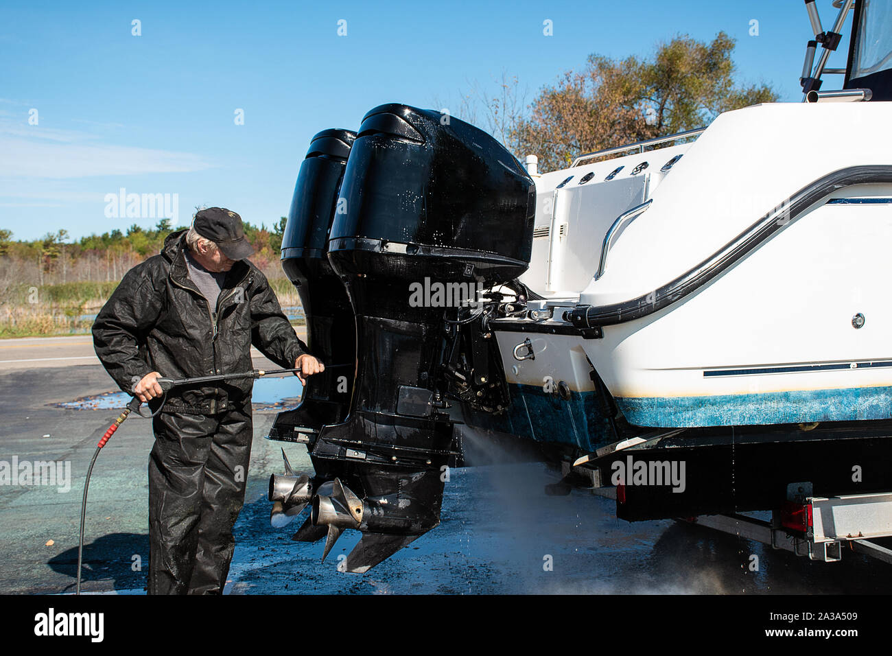 Uomo caucasico il lavaggio a pressione motori fuoribordo sul power boat Foto Stock