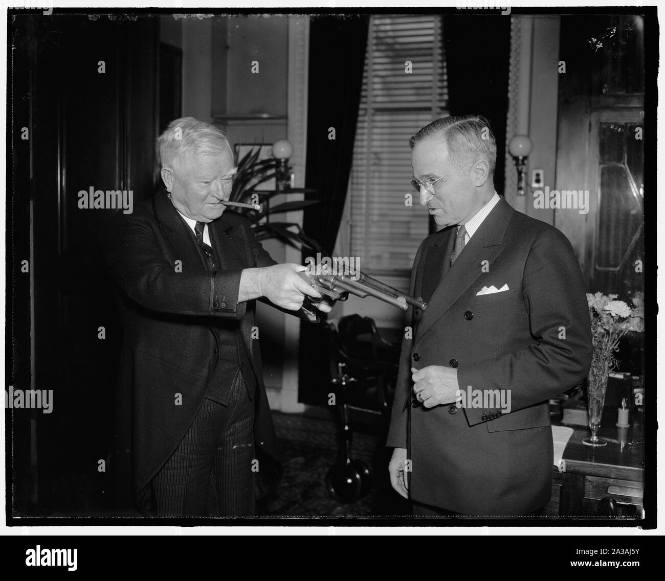 Stickup senatoriale. Washington D.C., Feb. 17. Dopo aver ispezionato un paio di 45 pistole di calibro precedentemente di proprietà di Jesse James, il famoso bandito di un'altra generazione, Vice Presidente Garner scherzosamente cerca la sua tecnica di stickup sul senatore Harry Truman del Missouri, attuale proprietario di pistole. Il senatore Truman fissato le pistole nel sud del Missouri da un medico la moglie il cui marito li abbia ricevuti in pagamento di prestazioni mediche rese Frank James, un altro del James' ragazzi. Jesse James in precedenza aveva lasciato loro a Frank dopo che egli è stato ucciso da uomini pinkton. Il bandito raccolto quasi un milione di dollari in una s Foto Stock