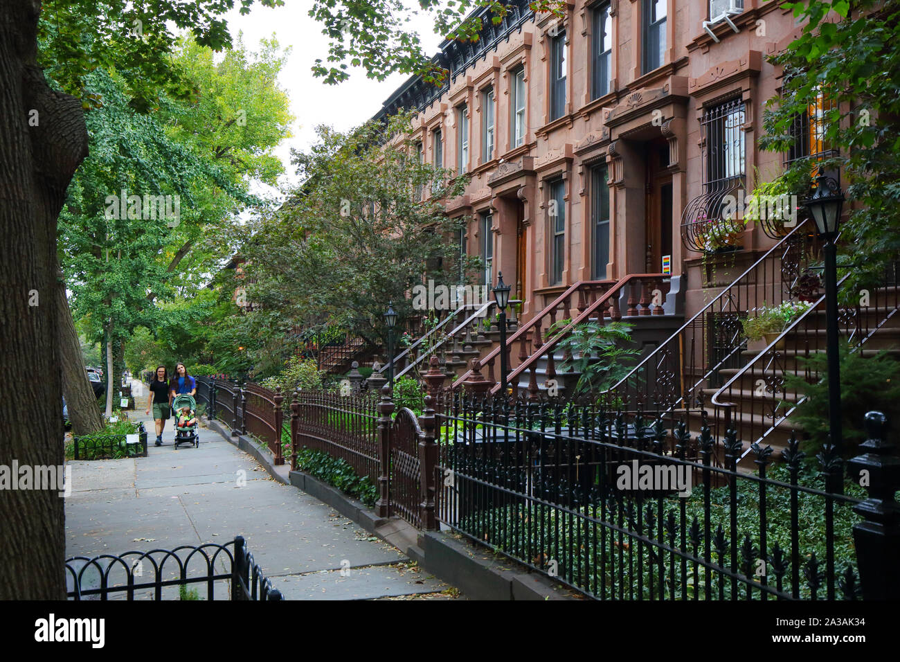 Persone con un passeggino a piedi passato case di arenaria trovata nel Park Slope quartiere di Brooklyn, New York City Foto Stock