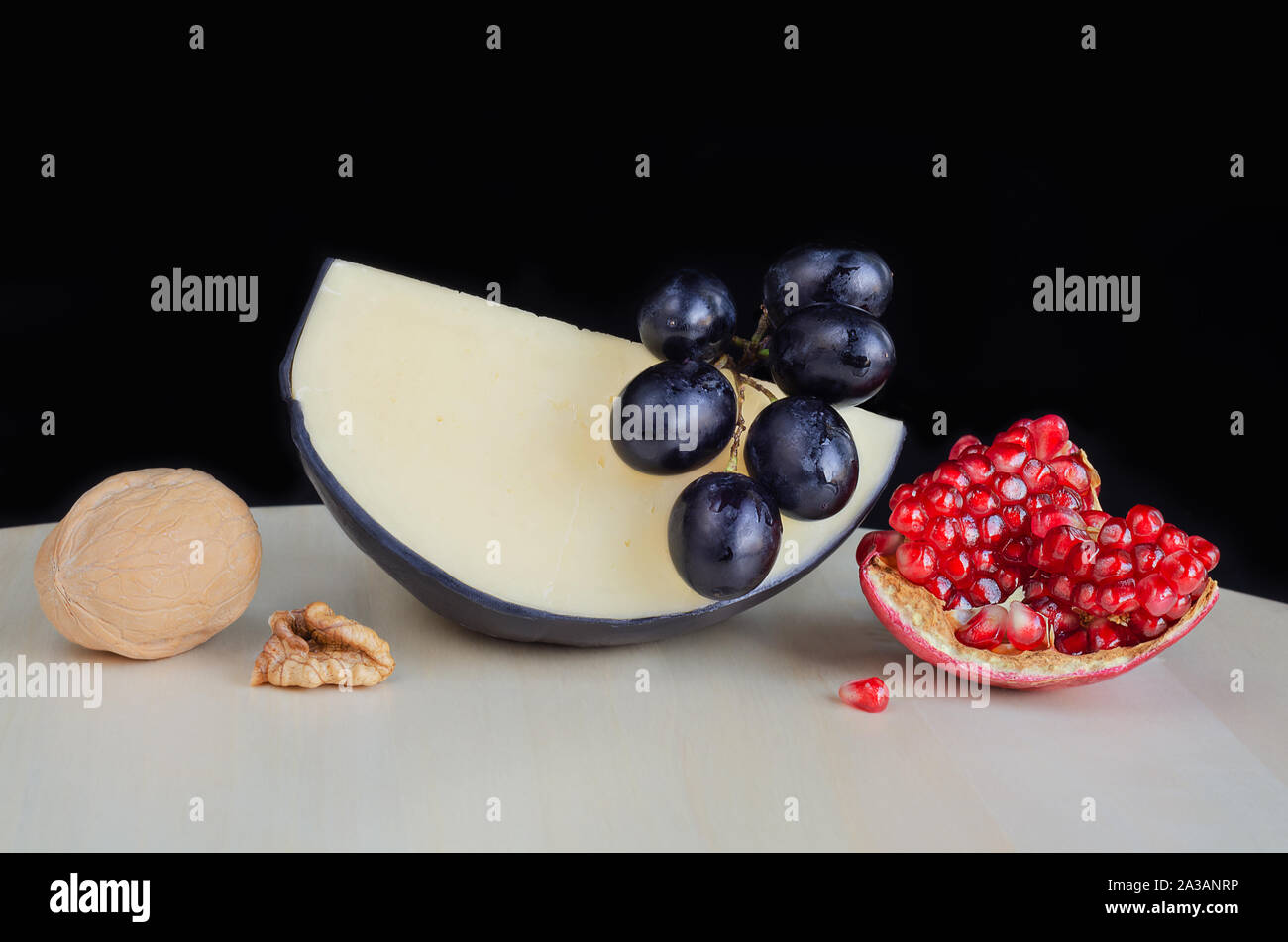 Formaggio a pasta dura e frutti vari sul tavolo. Sfondo nero Foto Stock