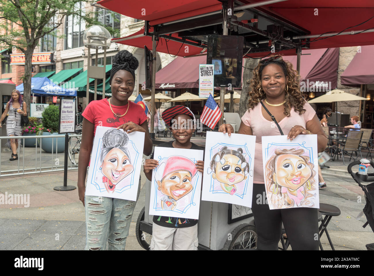 Shanice, Royal e Marquita Harris le caricature appena completato dal bozzetto artista Ben Bloss nel miglio-lungo 16th Street mall pedonale nel centro di Denver, Colorado. Marquita Harris detiene anche il disegno della sua figlia più giovane, Shanice Foto Stock