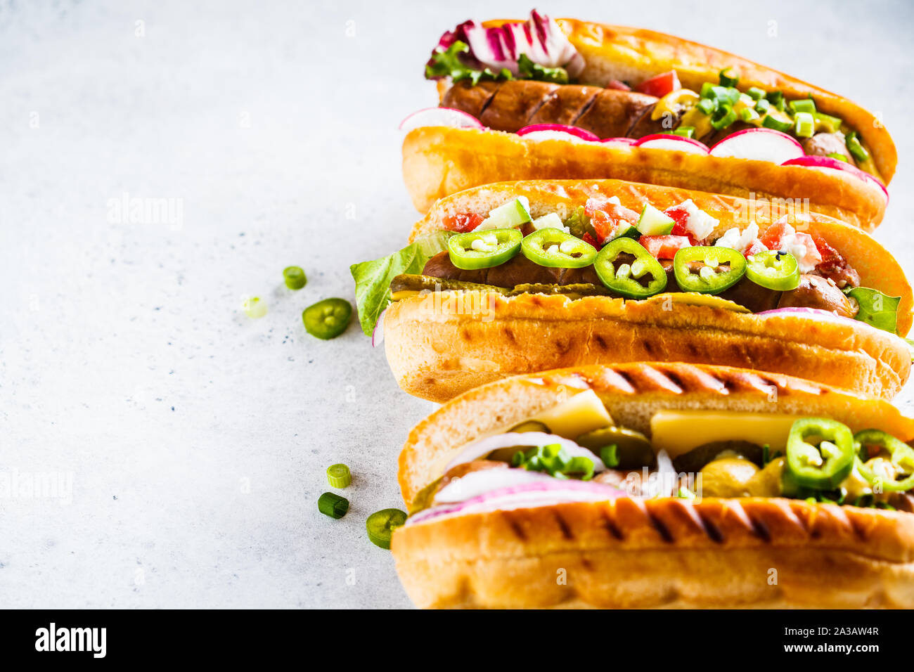Hot Dogs con diversi condimenti su uno sfondo bianco, copia dello spazio. Il fast food concept. Foto Stock