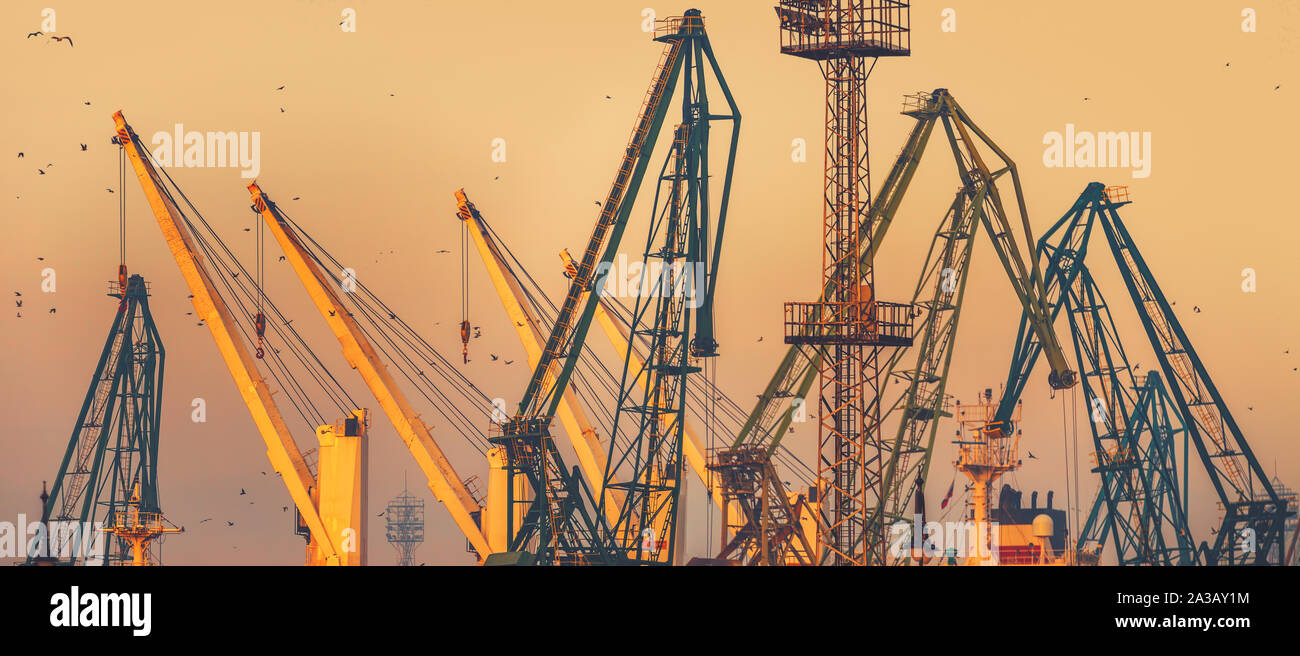 Tramonto sulla gru industriali a livello commerciale porto di mare della città di Varna, Bulgaria immagine Foto Stock