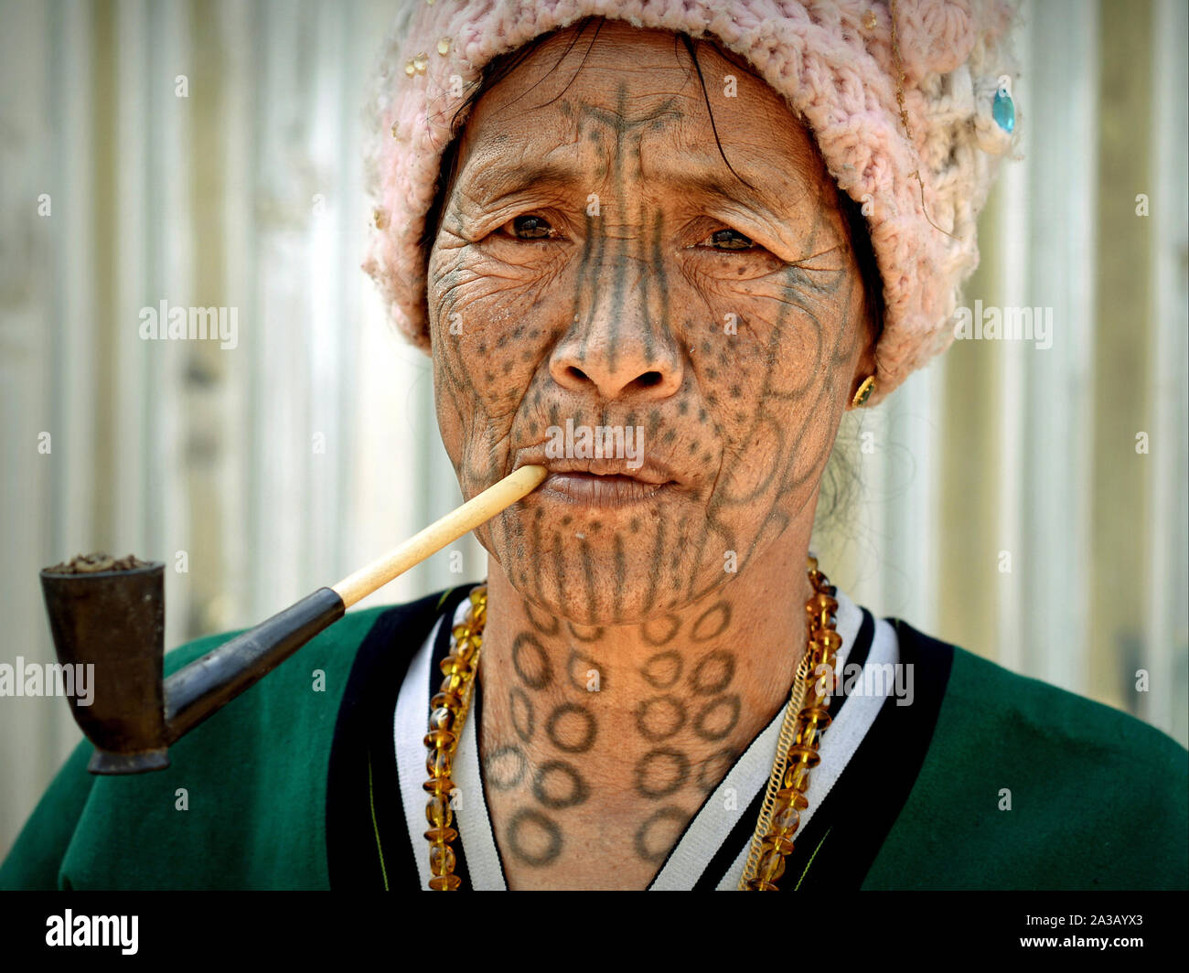 Anziani mento Muun hill-tribe donna ('sdonna ragno') con i tradizionali tatuaggi facciali fuma una tubazione con tabacco locale. Foto Stock