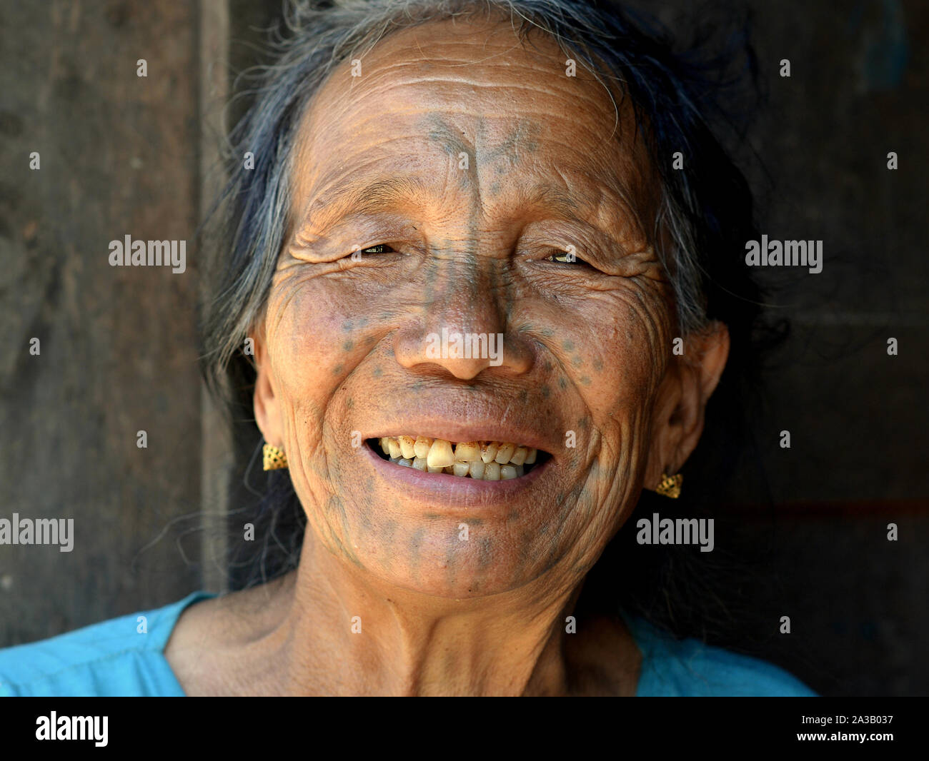 Vecchio mento Muun donna tribale ('sdonna ragno') con una sbiadita tradizionali tatuaggi facciali sorrisi per la fotocamera. Foto Stock