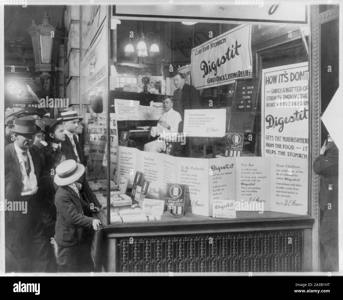 Shoppers guardando la finestra di visualizzazione del Brown's Drug Store, pubblicità Digestit, un stomaco sollievo medicina di brevetto; prodotto viene vistato da un pianista, il sig. Thomas, che è stata riprodotta nella vetrina di un negozio non-stop per 60 ore e 45 minuti; il sig. W.L. Marrone in piedi dietro il sig. Thomas. Foto Stock