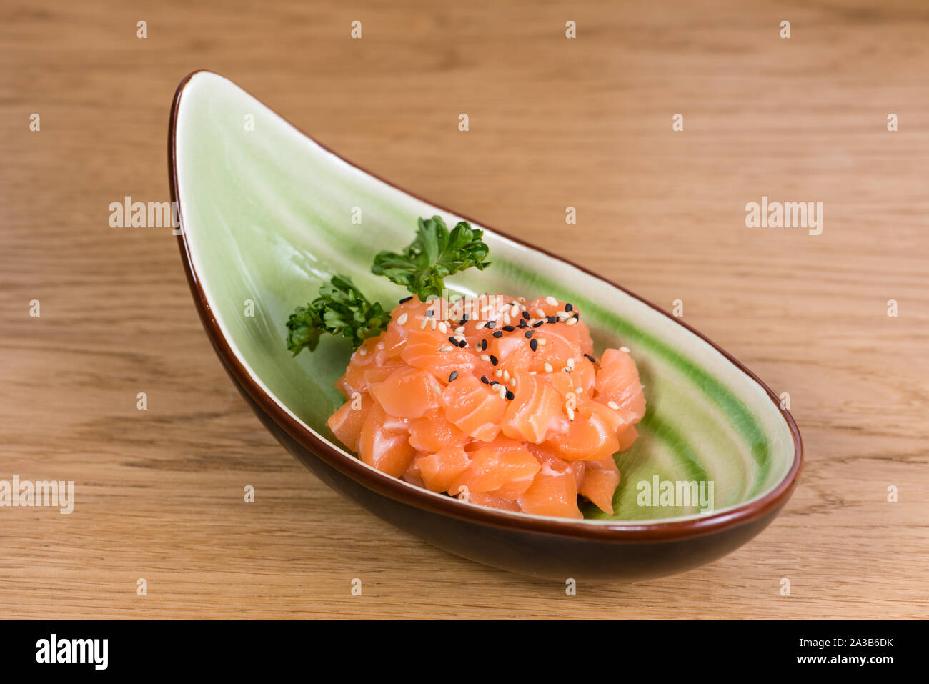 Tartara di salmone fresco con in bianco e nero di sesamo, servita su una barca a forma di lastra Foto Stock