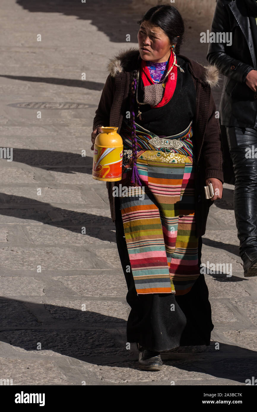 Una donna tibetana pellegrino in abito tradizionale, incluso il suo colorato o bangdian pangden grembiule, visita al monastero di Drepung vicino a Lhasa, in Tibet. Foto Stock