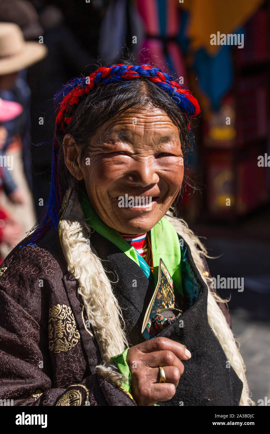 Una donna più anziana dalle montagne del Tibet orientale in un tradizionale chupa robe in pellegrinaggio a Lhasa, in Tibet. Foto Stock