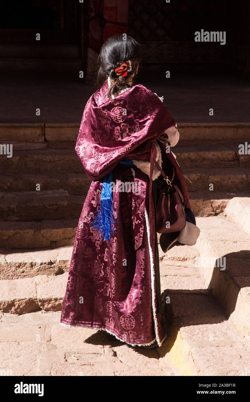 Una giovane donna tibetana indossa un elegante pelle di montone foderato di seta o chupa chuba coat su un religioso pellegrinaggio al monastero di Drepung vicino a Lhasa, in Tibet. Foto Stock