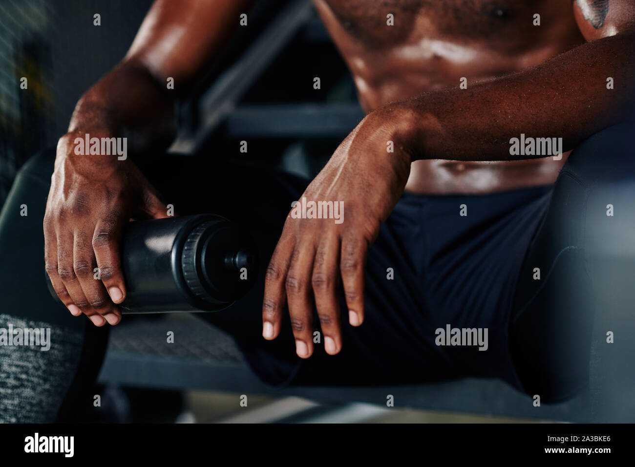 Immagine ritagliata di giovani montare uomo seduto sui gradini con bottiglia di plastica di acqua e riposo dopo un allenamento intenso Foto Stock