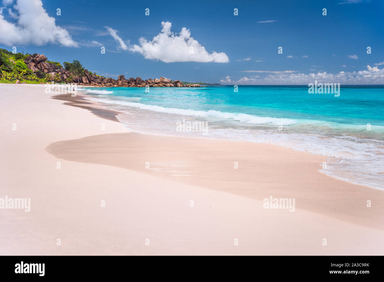 Grand Anse sabbiosa spiaggia esotica al La Digue Island alle Seychelles. I turisti non riconosciuta di nuoto e relax nella laguna blu in background Foto Stock