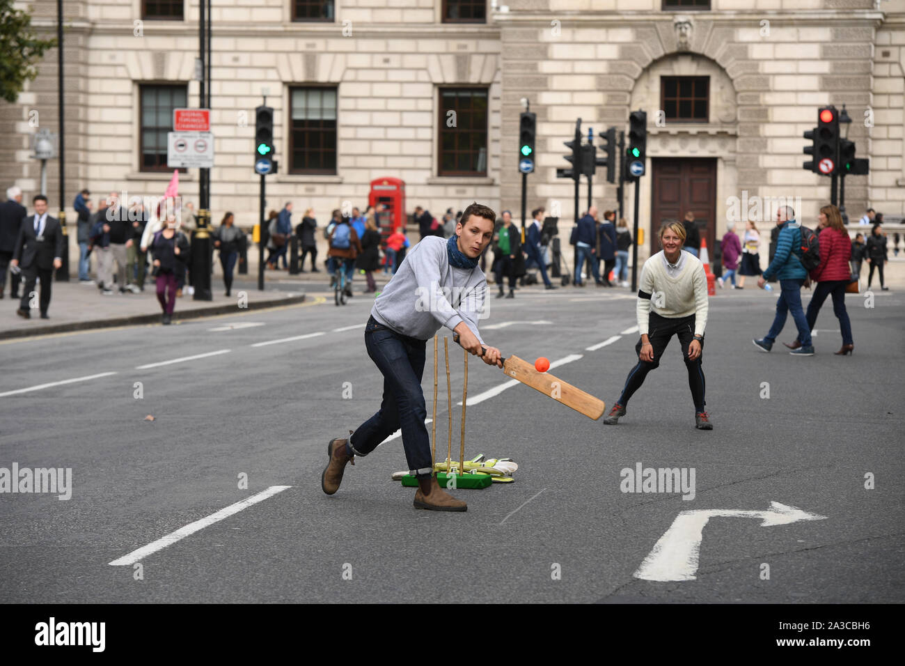 I dimostranti di giocare una partita di cricket durante una ribellione di estinzione protesta in Westminster, Londra. Foto Stock