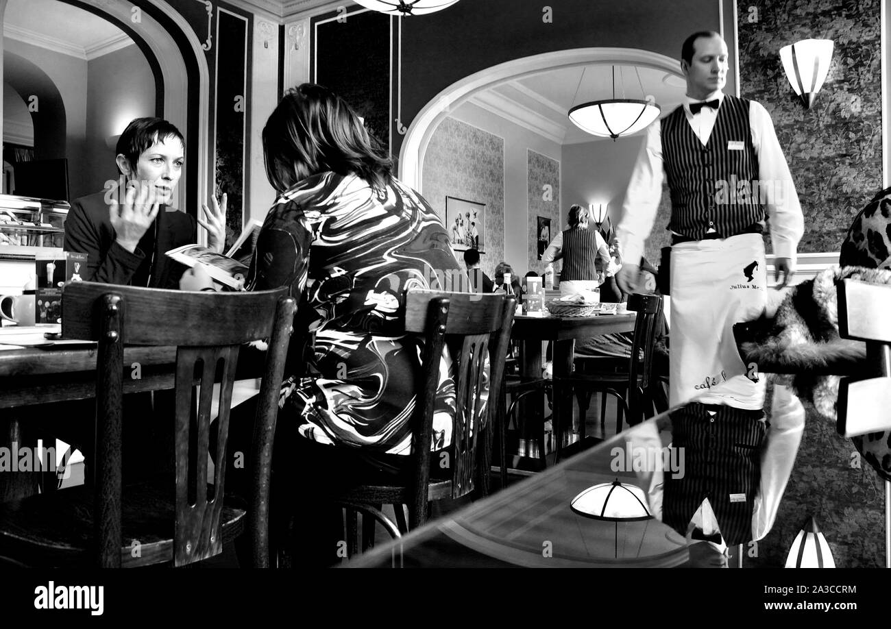 Praga, Repubblica Ceca. Cafe Louvre - conversazione tra due donne, cameriere Foto Stock