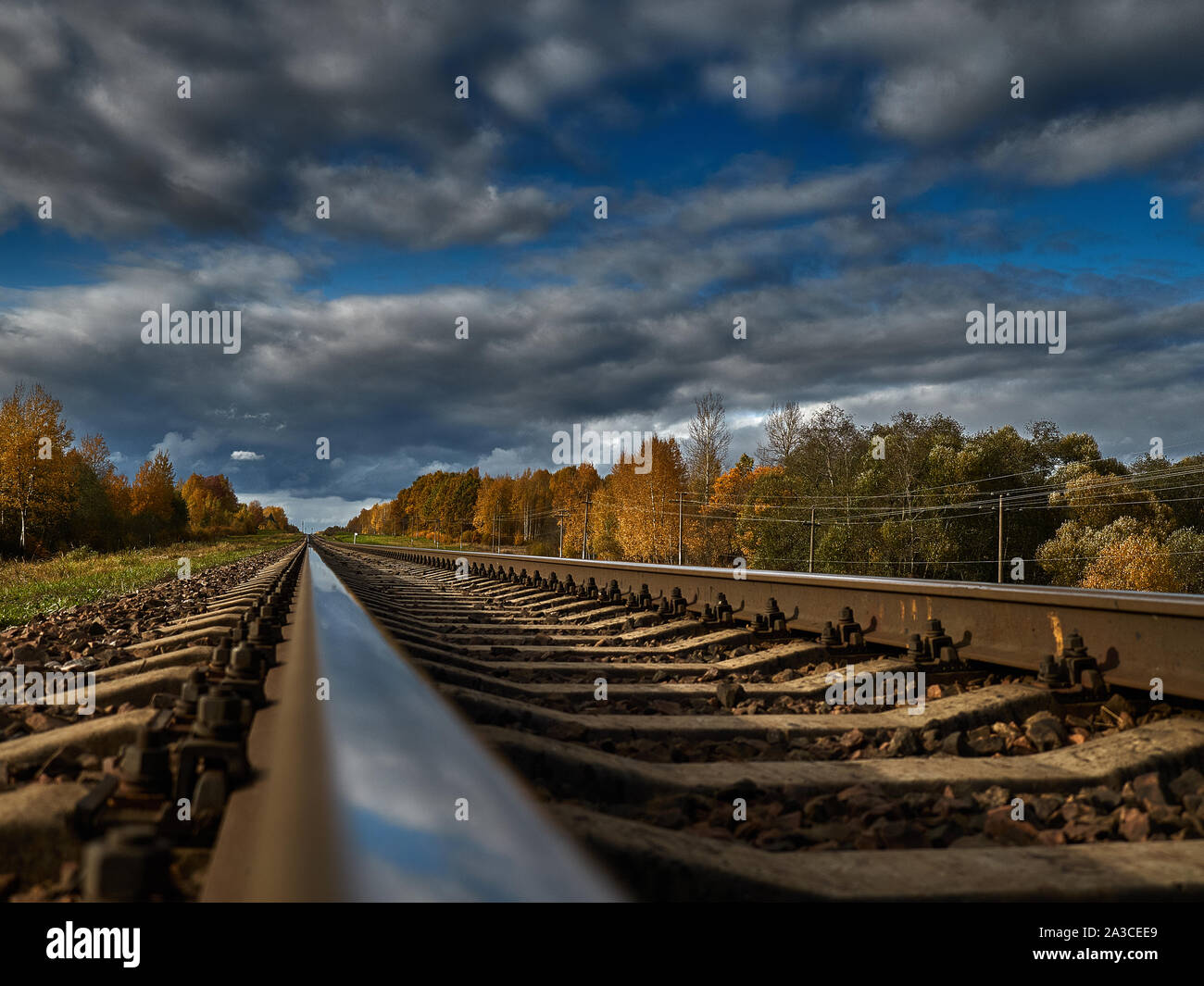 La strada ferrata contro lo sfondo di un azzurro cielo di autunno va all'infinito. Foto Stock