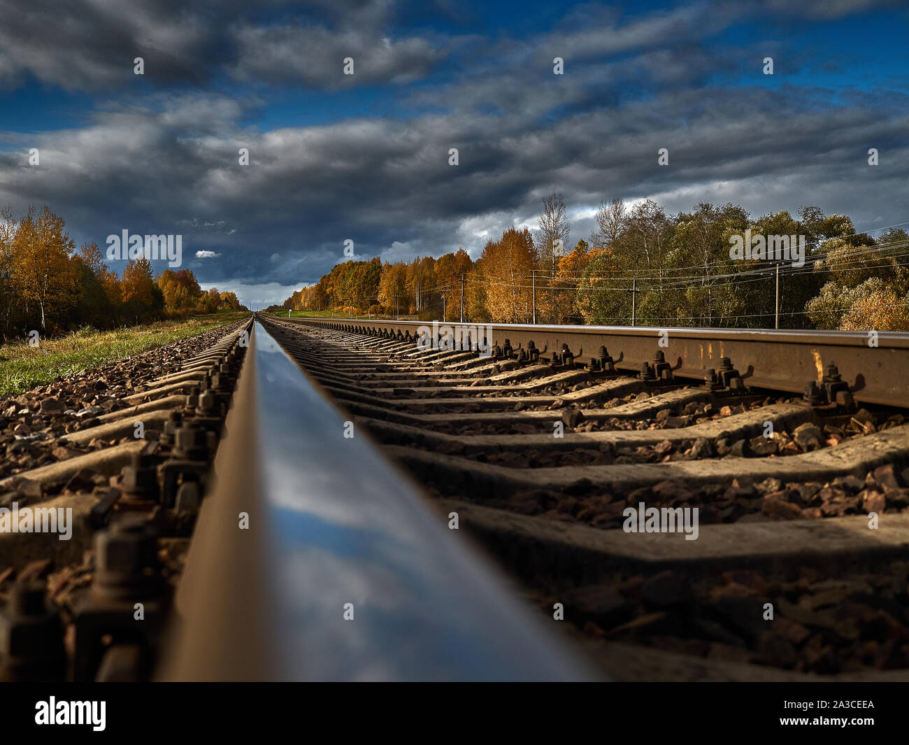 La strada ferrata contro lo sfondo di un azzurro cielo di autunno va all'infinito. Foto Stock