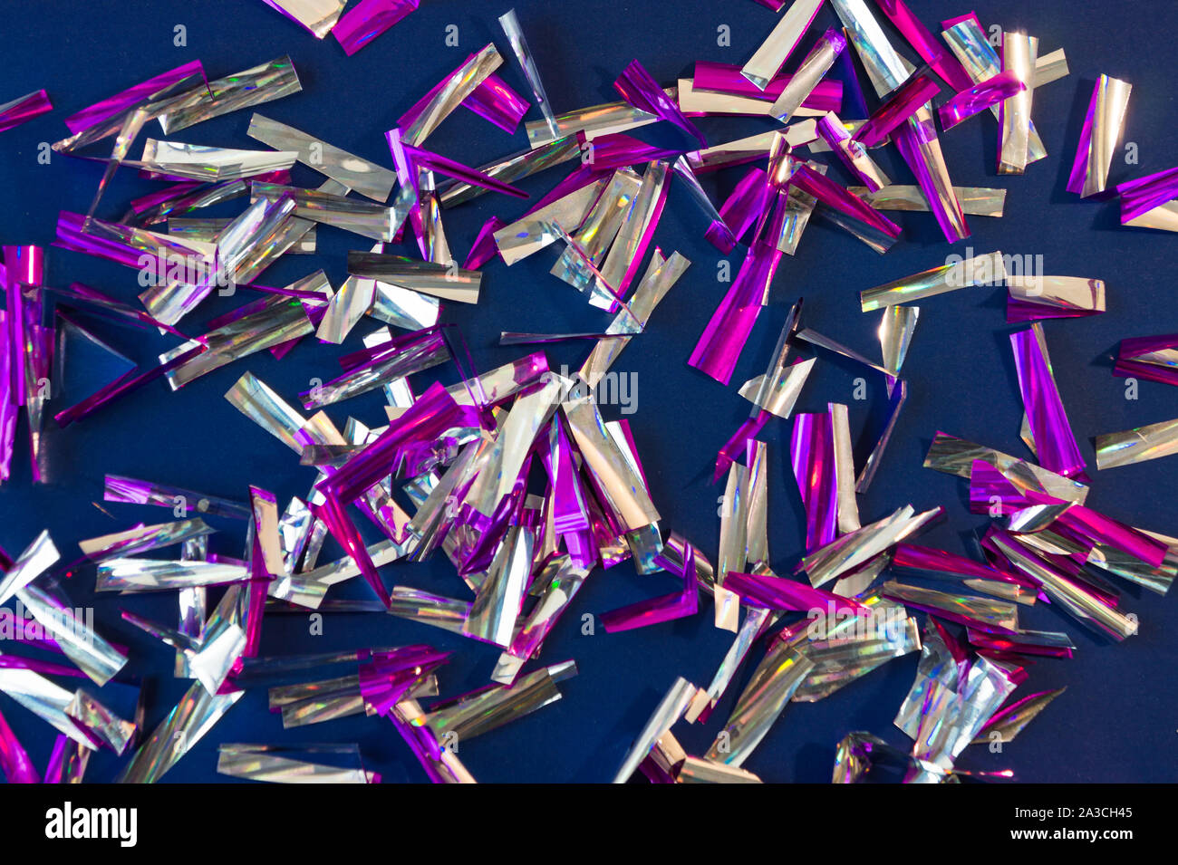 Foto di sfondo di confetti di forma rettangolare realizzato in viola e lamina d'argento su sfondo blu scuro. Foto Stock