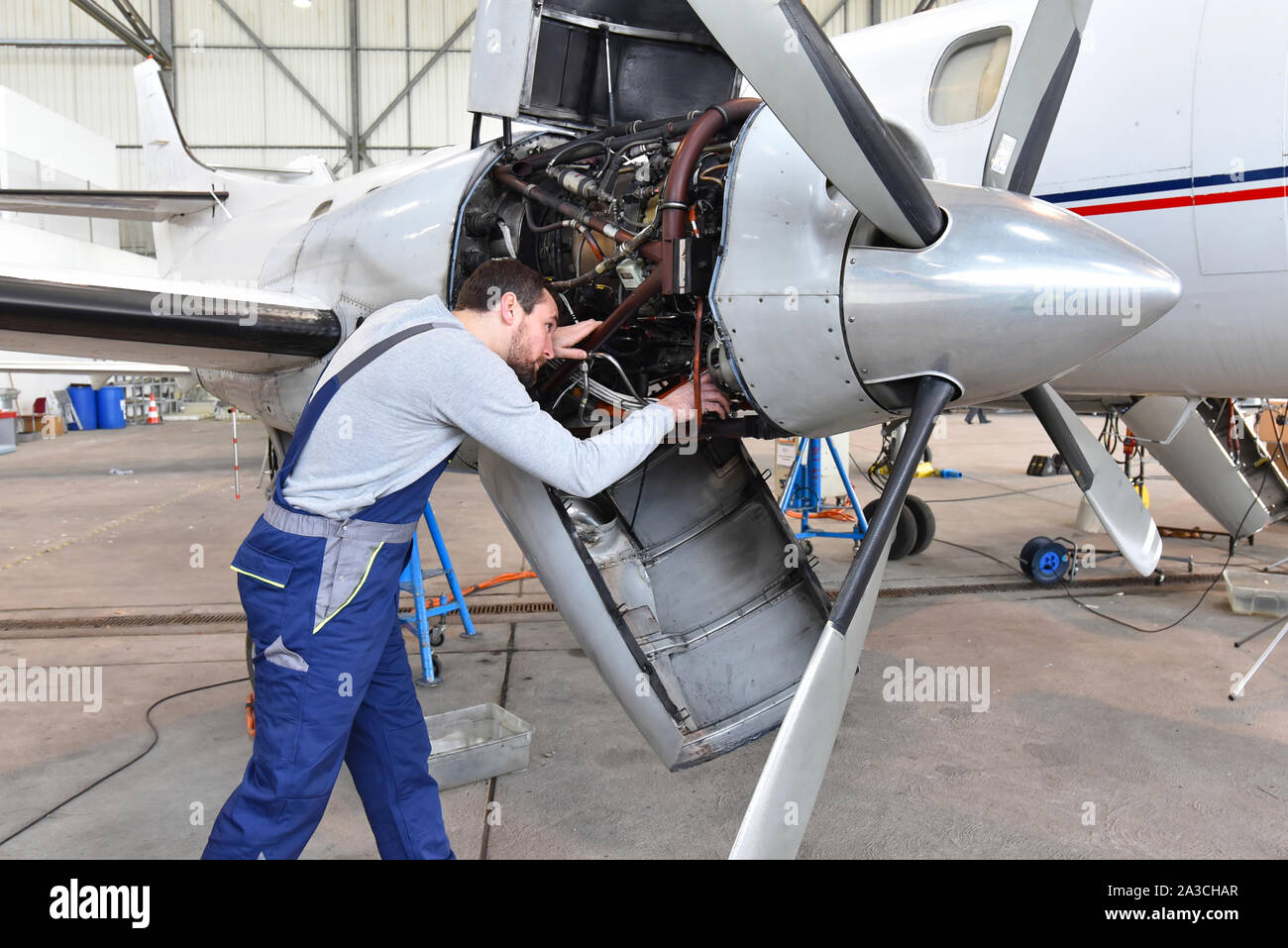 Meccanico aeronautico ripara un motore aeronautico in un hangar aeroporto Foto Stock