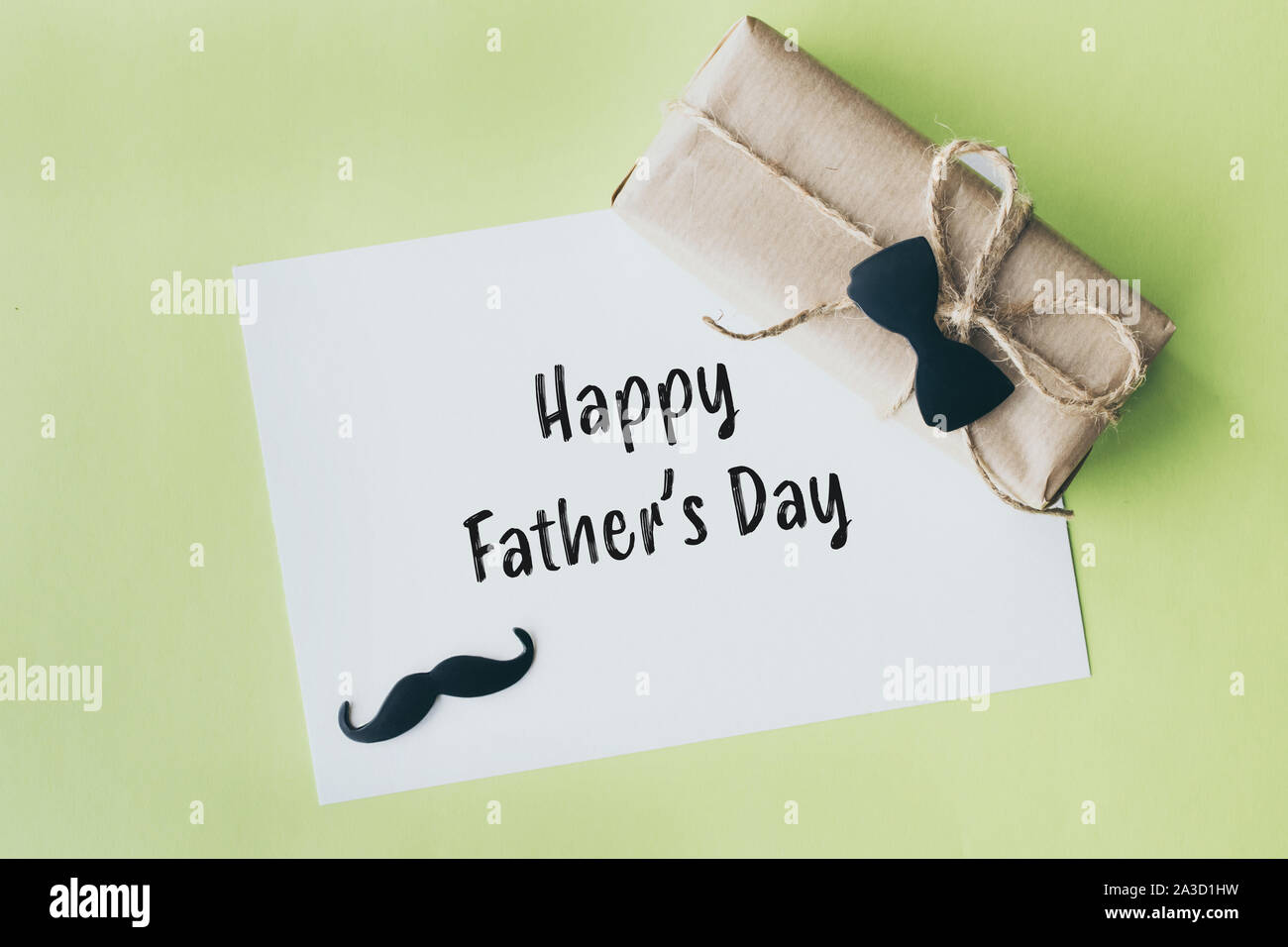 La festa del papà. Pacchetto regalo avvolto con della carta e corda con un fiocco decorativo tie-in su sfondo verde Foto Stock