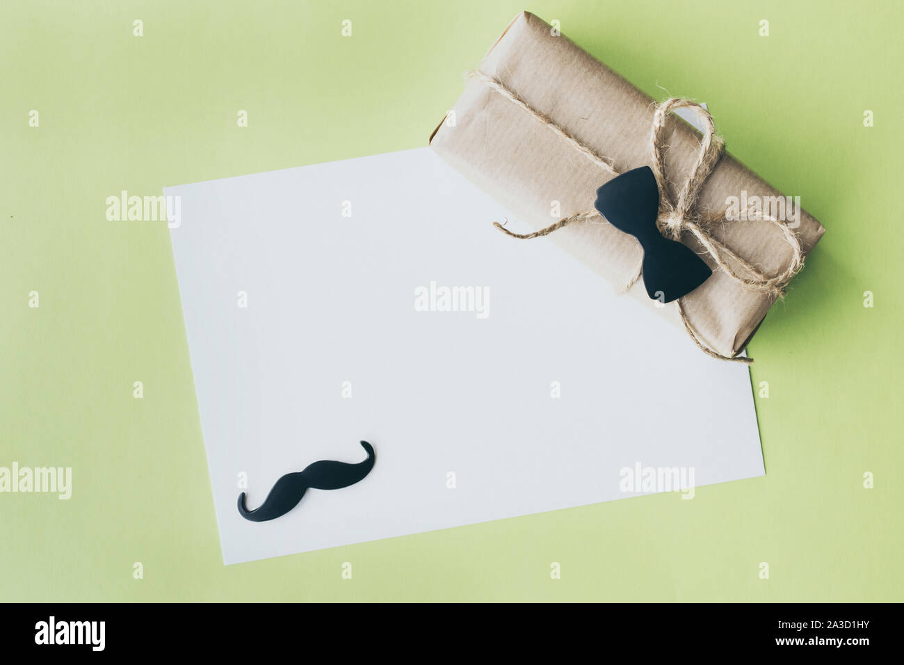 La festa del papà. Pacchetto regalo avvolto con della carta e corda con un fiocco decorativo tie-in su sfondo verde. Copyspace Foto Stock